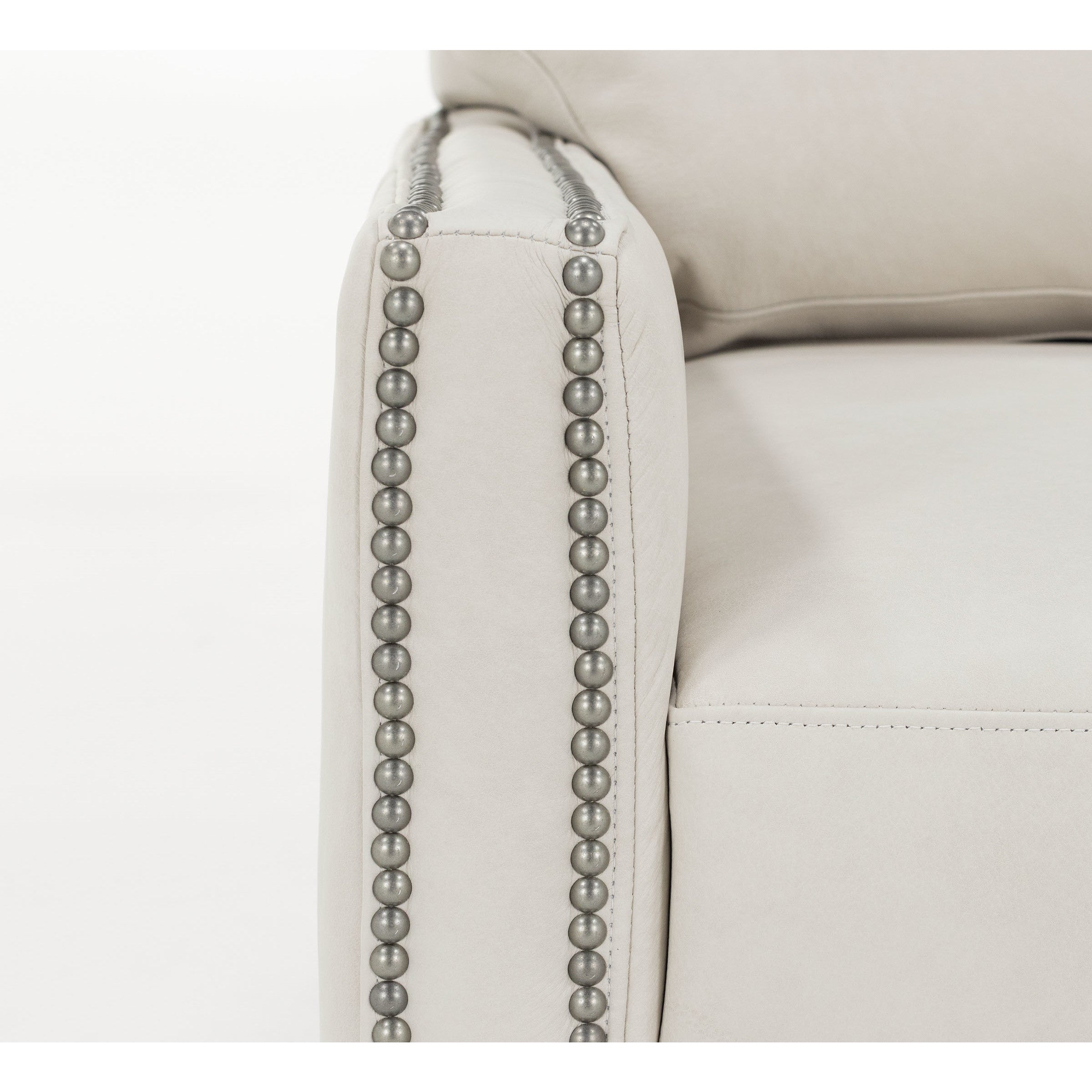 Close-up of a light-colored sofa arm with decorative nailhead trim.