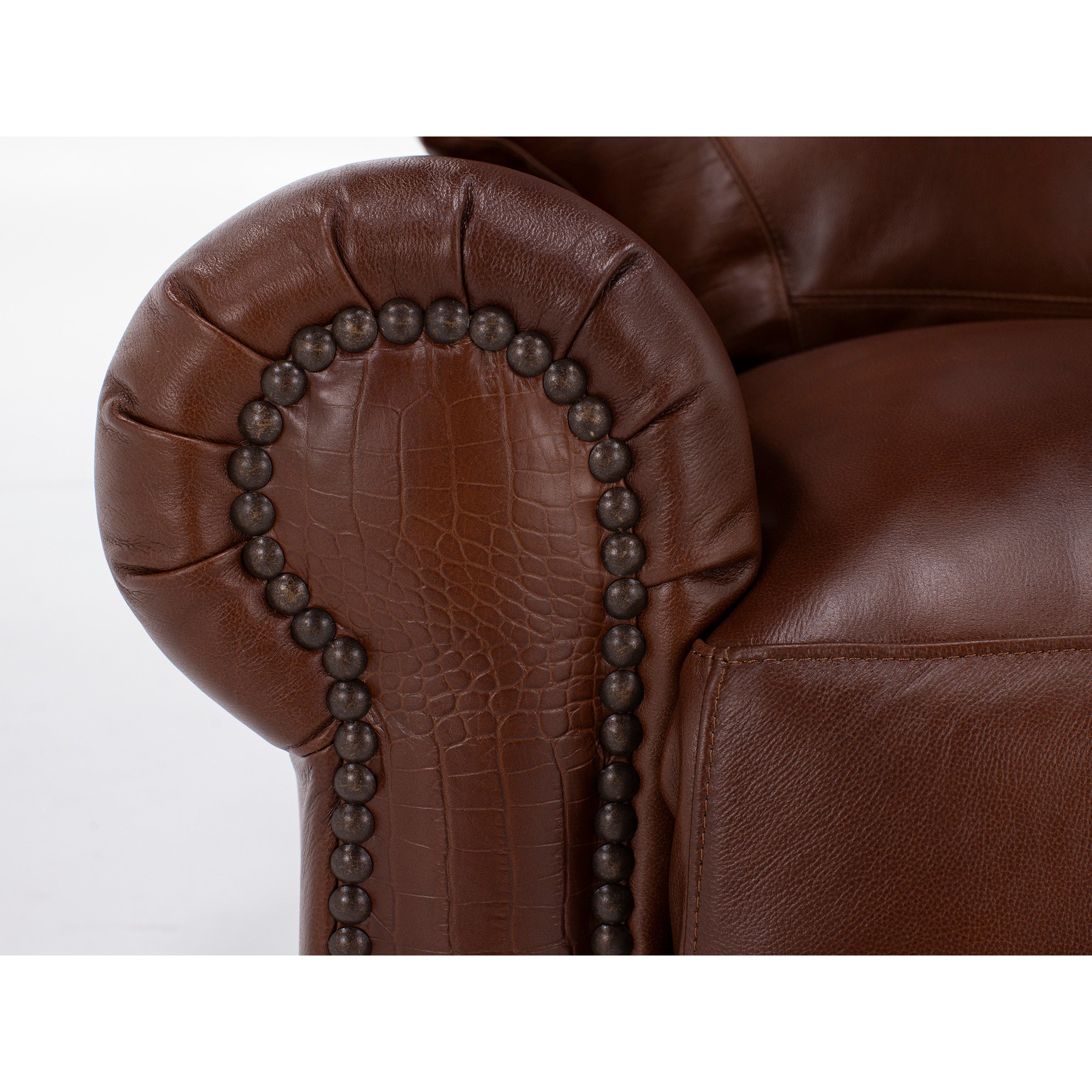 Close-up of brown leather sofa armrest with decorative nailhead trim.