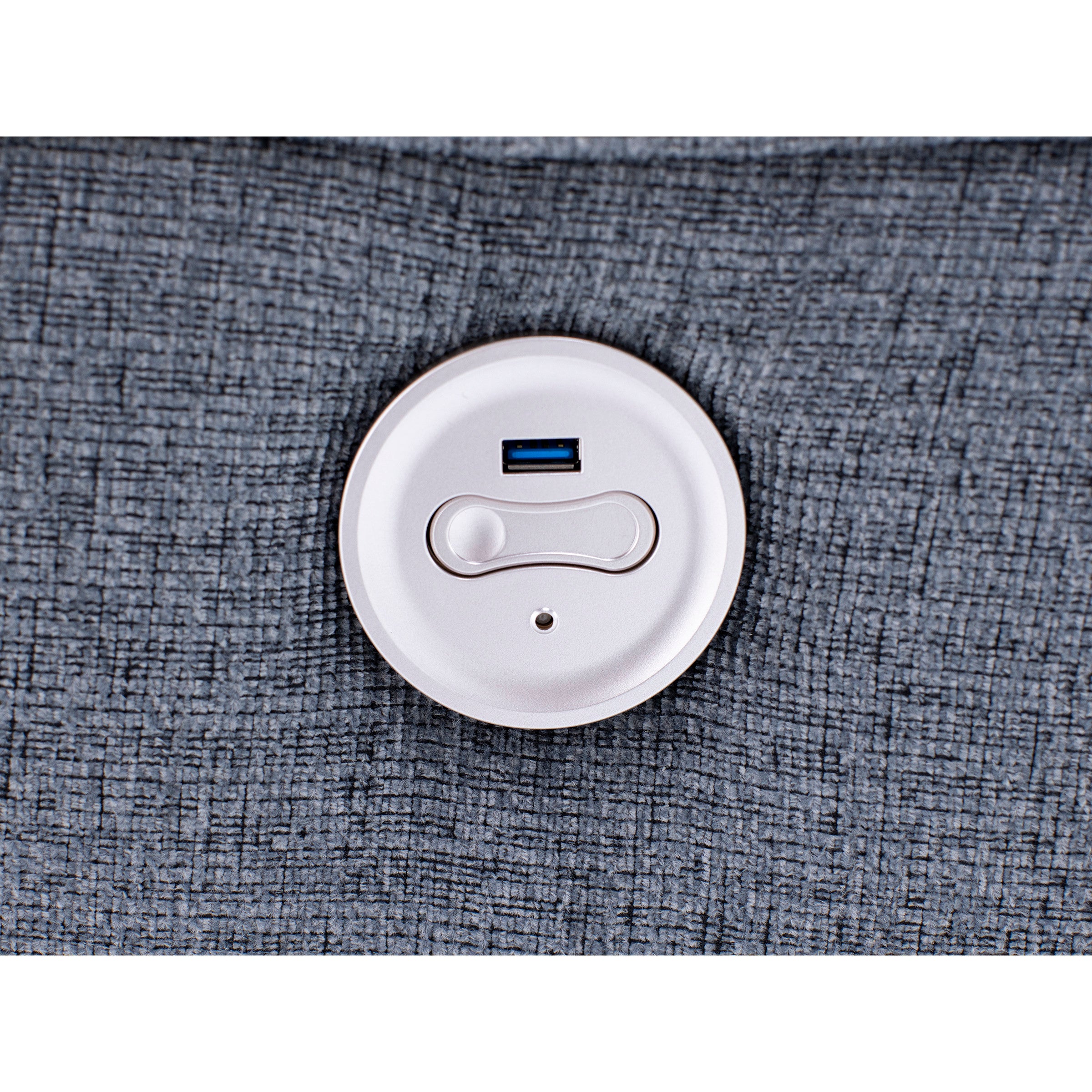 Close-up of a round USB port panel on textured gray fabric.
