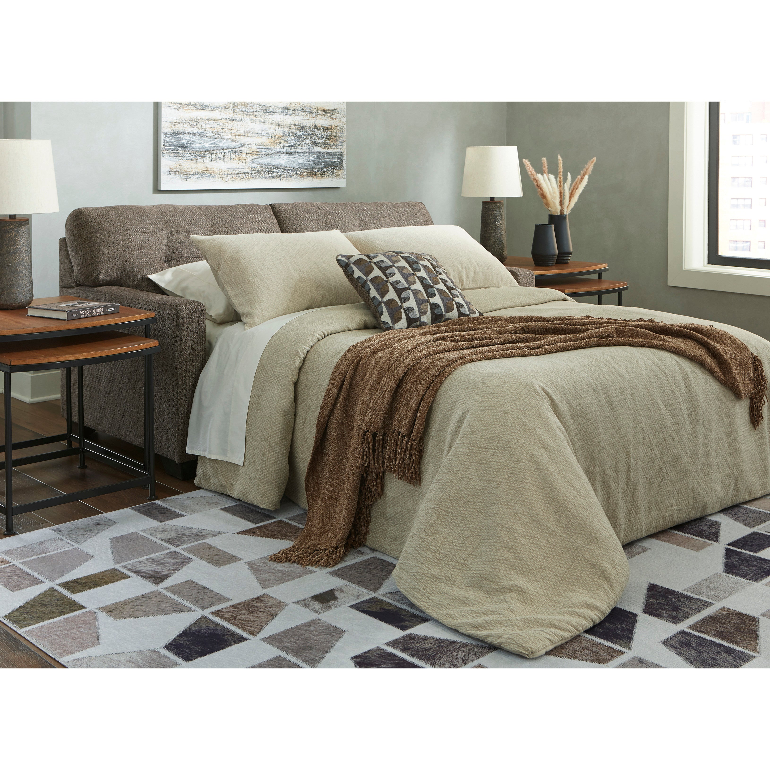 Modern bedroom with beige bedding, brown throw blanket, and geometric rug.