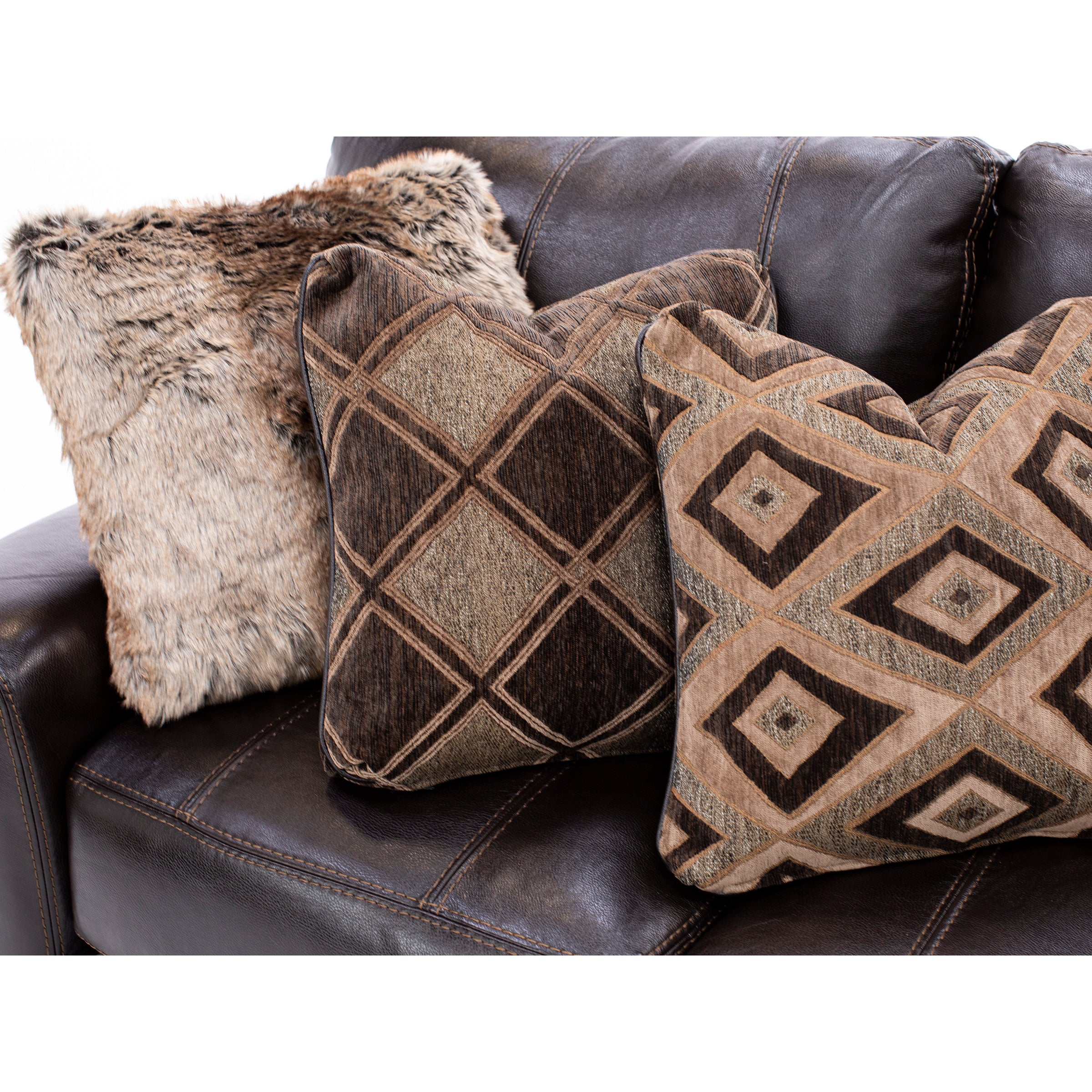 Three patterned throw pillows on a dark brown leather couch.