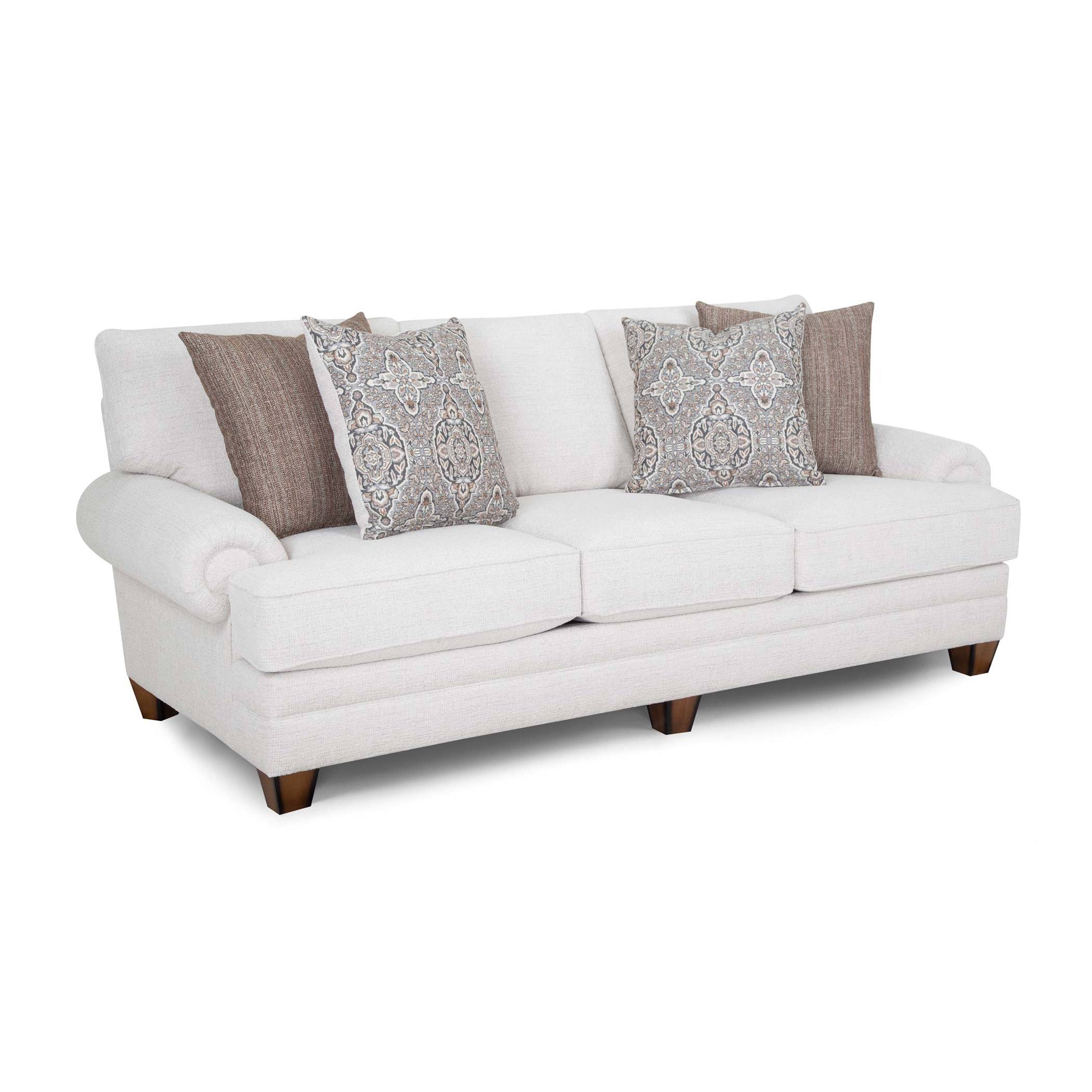 Light beige sofa with rolled arms, wooden legs, and four decorative pillows.