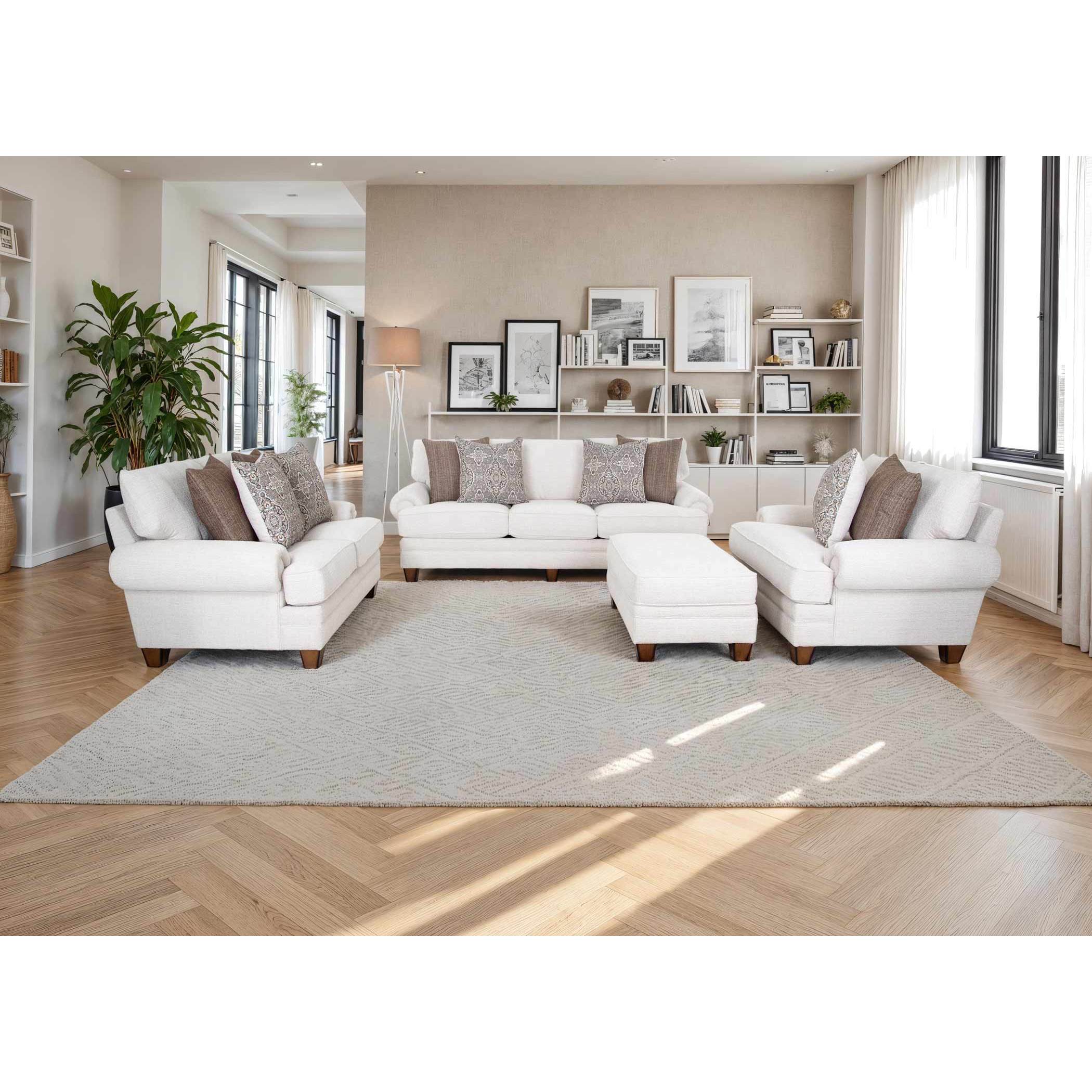 Bright living room with three white sofas, accent pillows, ottoman, and shelves with decor.