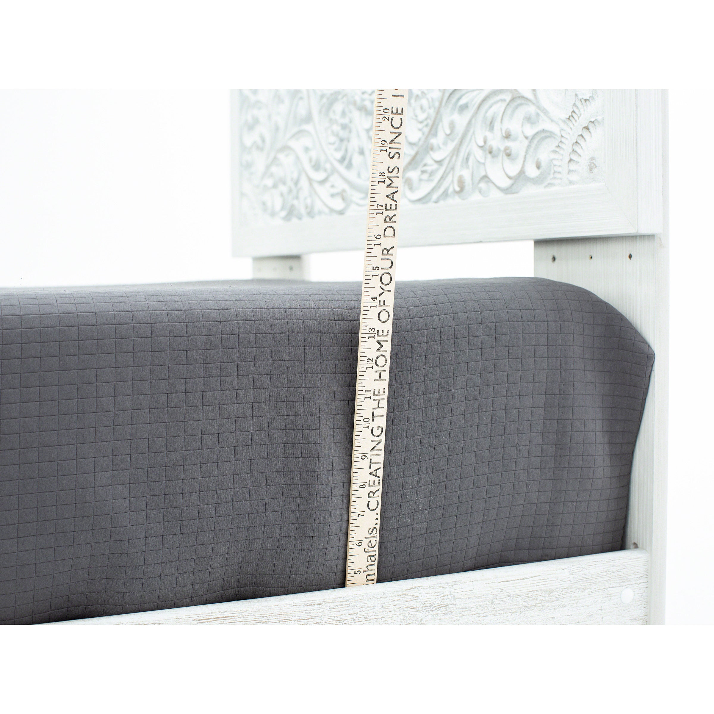 Grey fitted sheet on a bed with a ruler measuring its pocket depth.