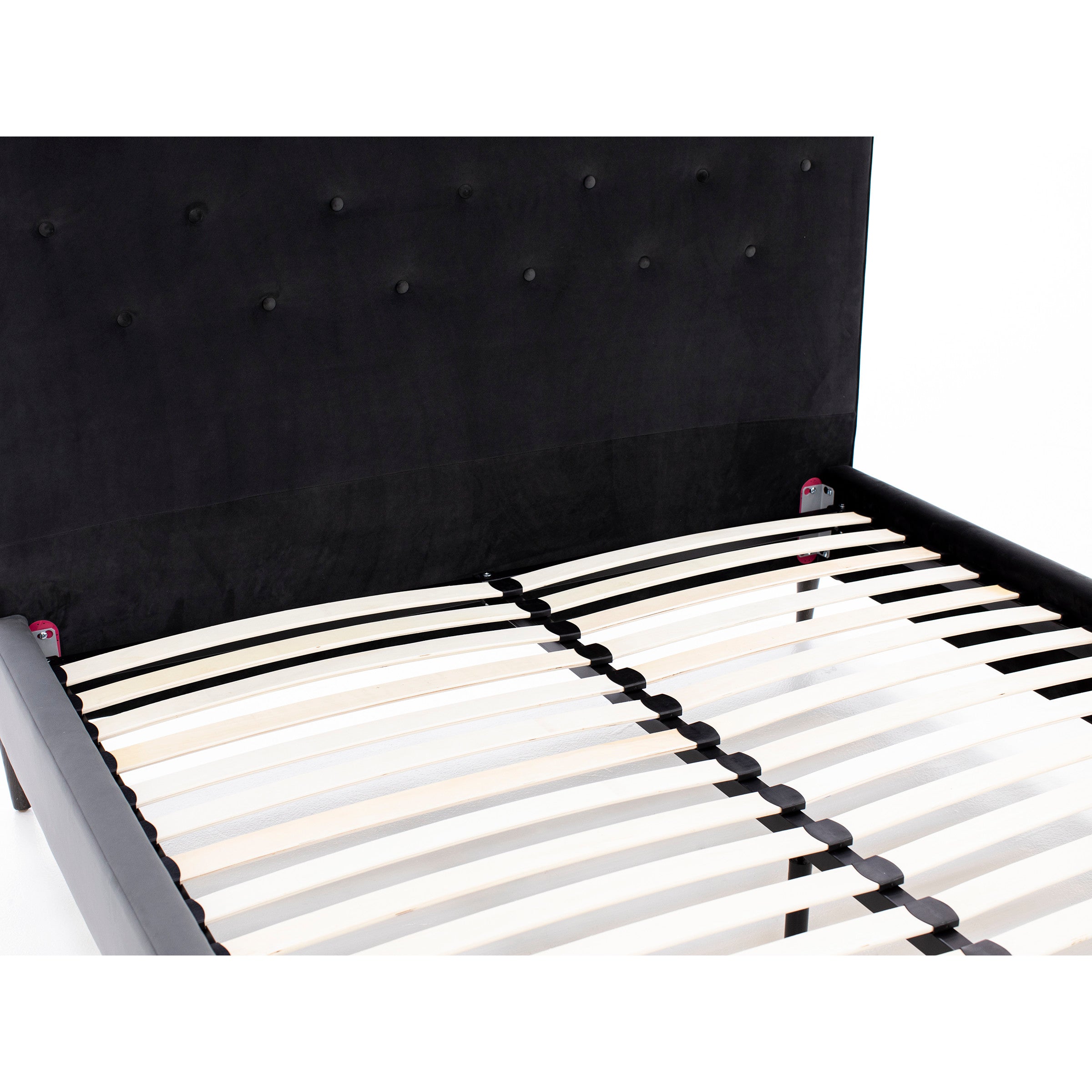 Close-up of a black bed frame with wooden slats and tufted headboard.