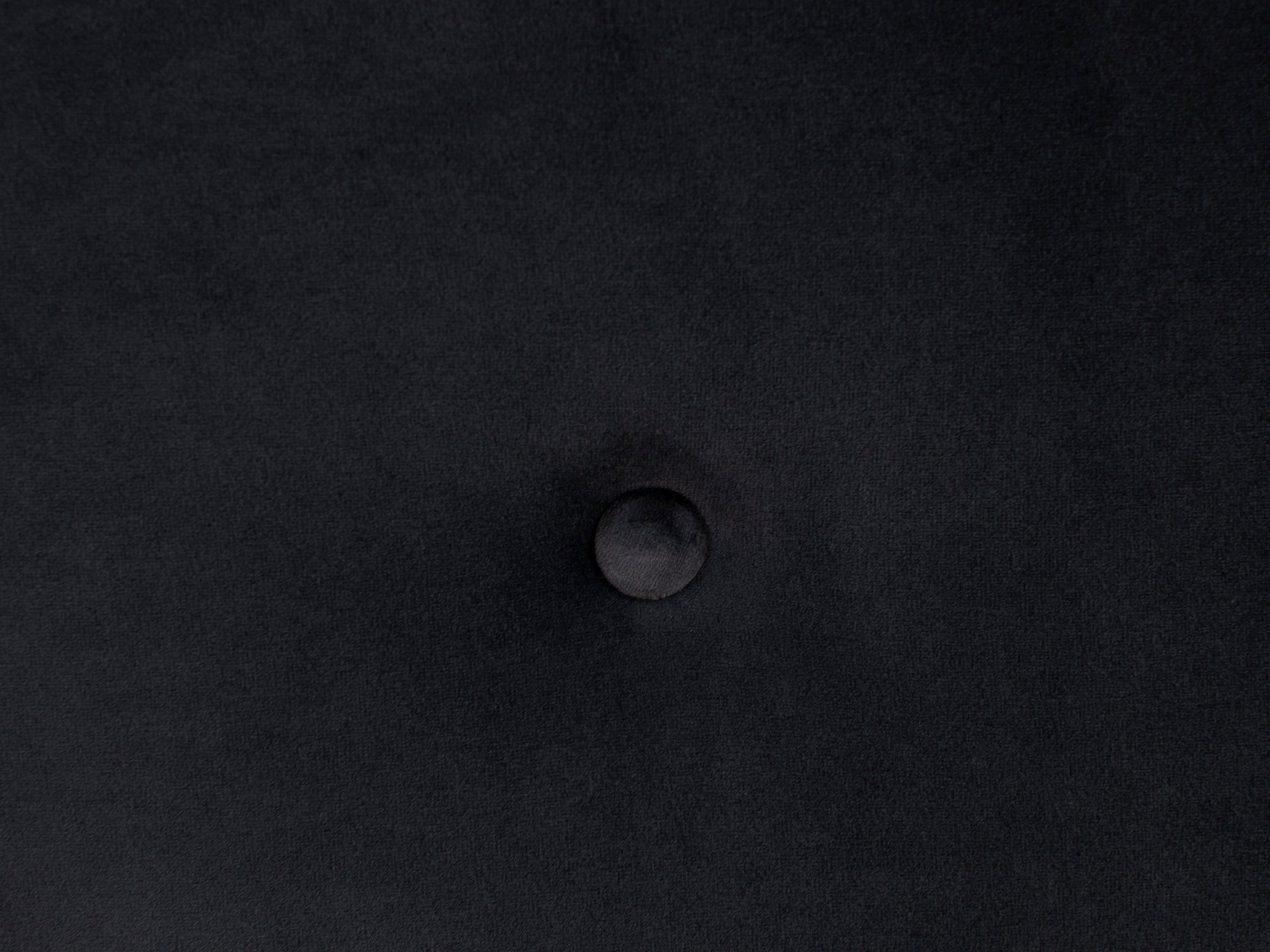 Close-up of a dark fabric surface with a centered button tuft.
