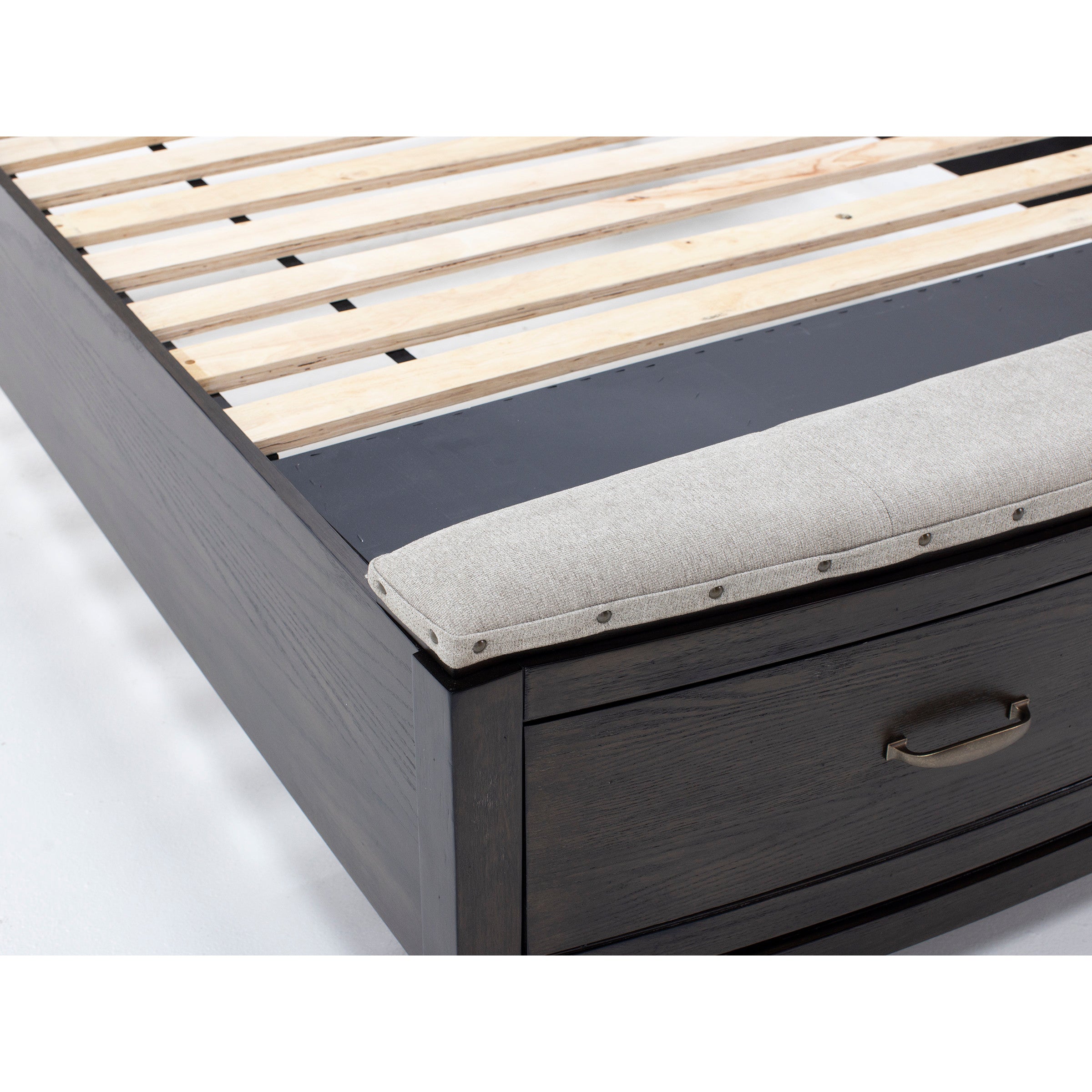 Close-up of a dark wood bed frame with slatted base, storage drawer, and padded fabric bench.