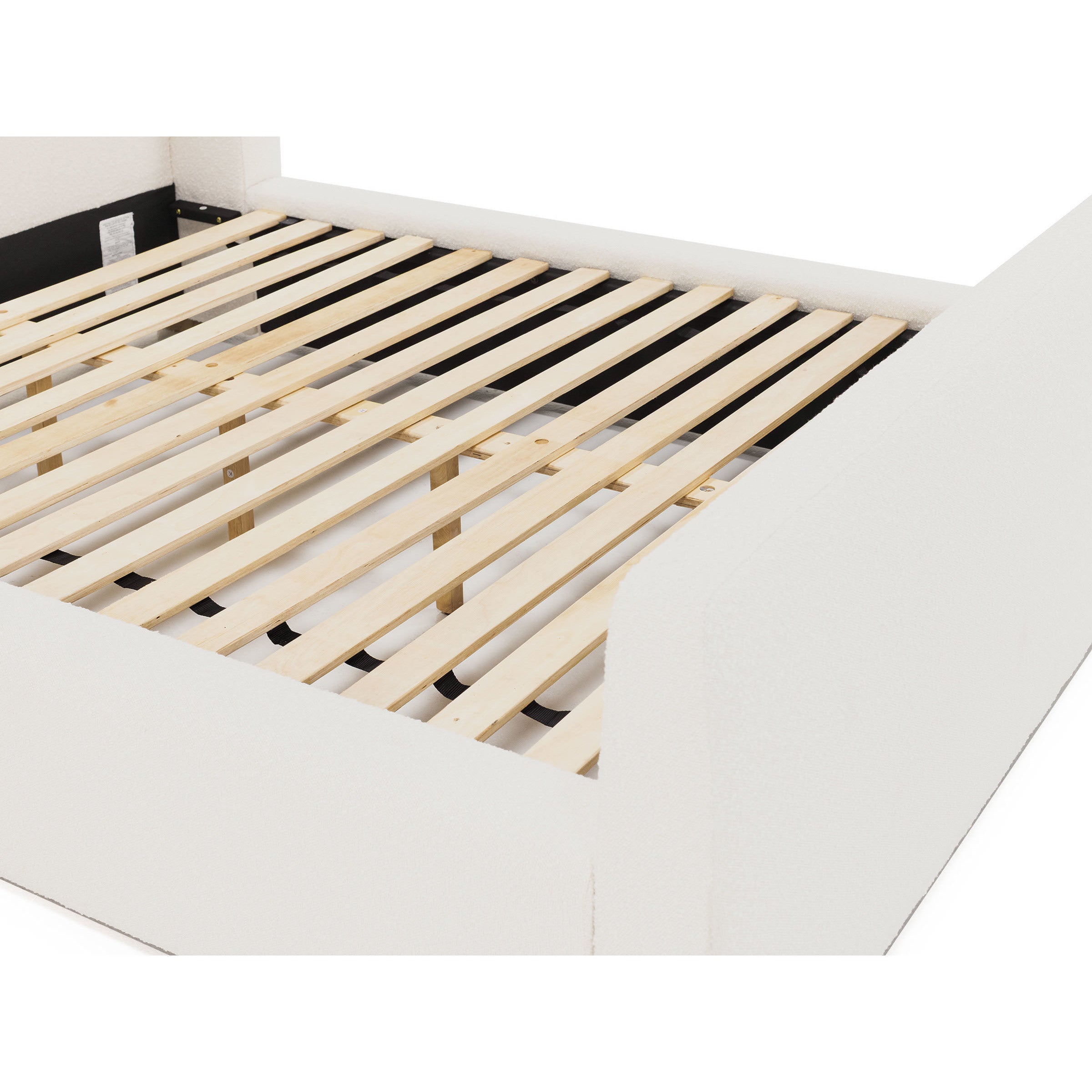 Close-up of a bed frame with wooden slats and white upholstered sides.