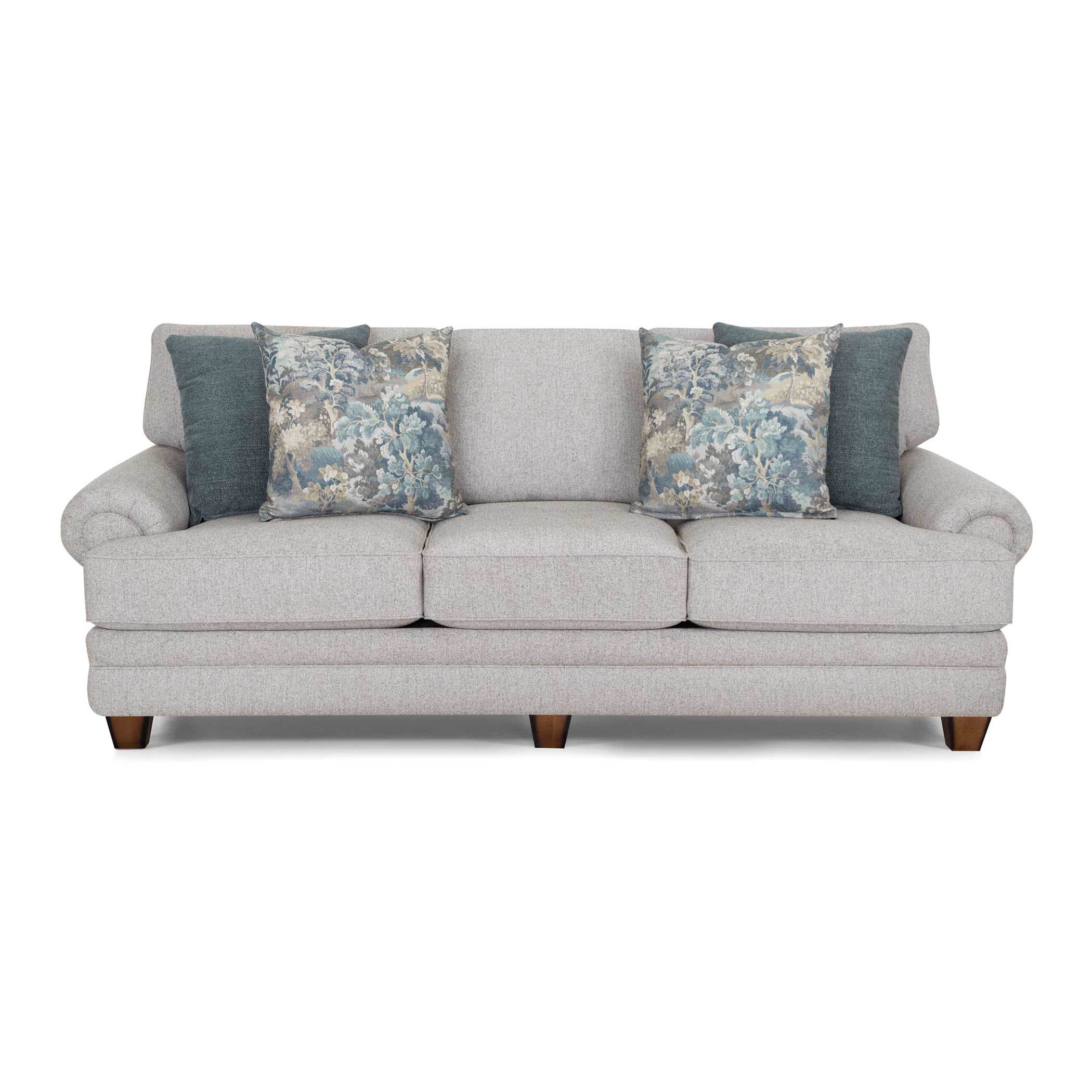 Light gray sofa with four blue accent pillows, two solid and two floral.