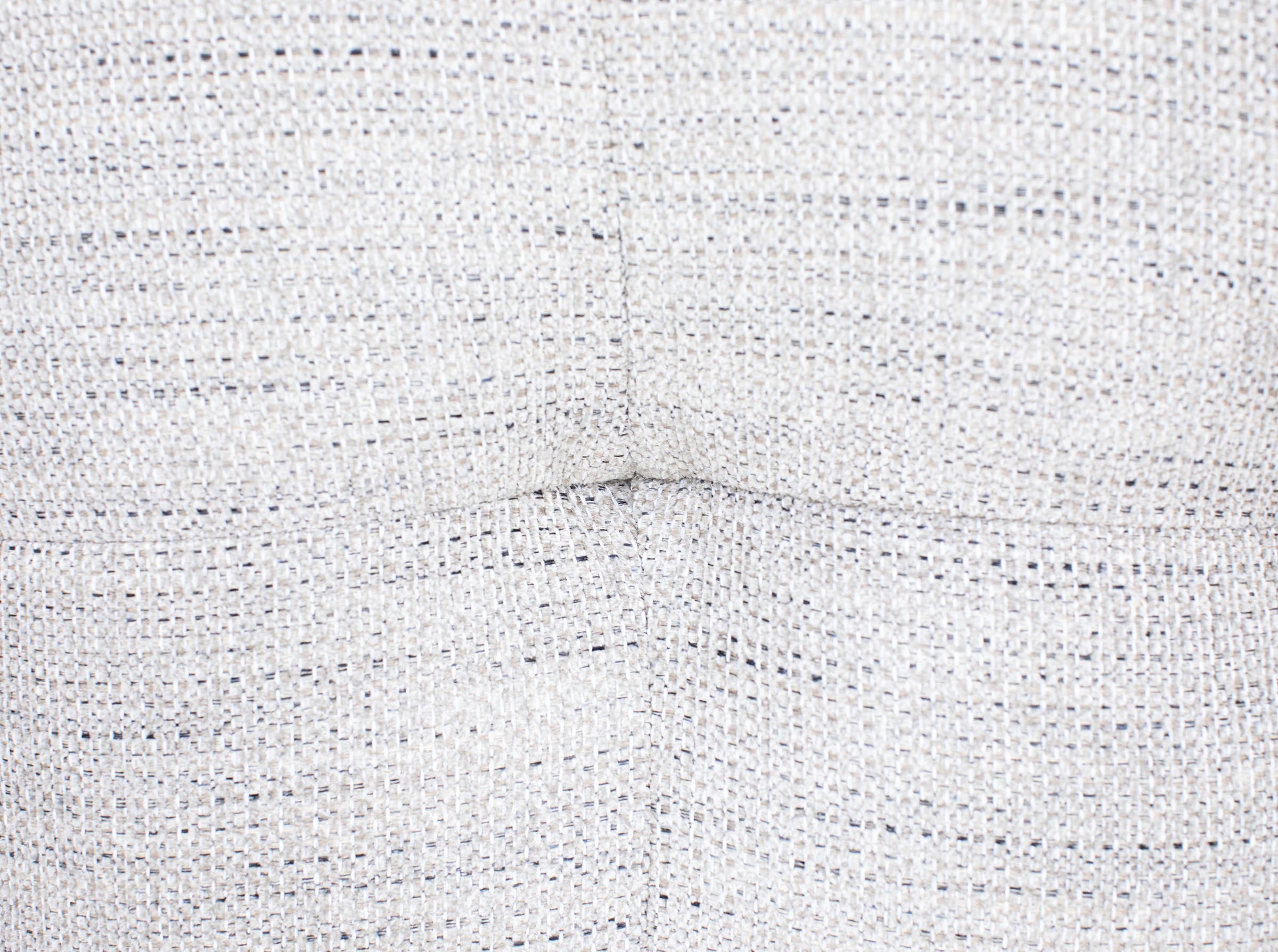 Close-up of light gray textured fabric with visible stitching.