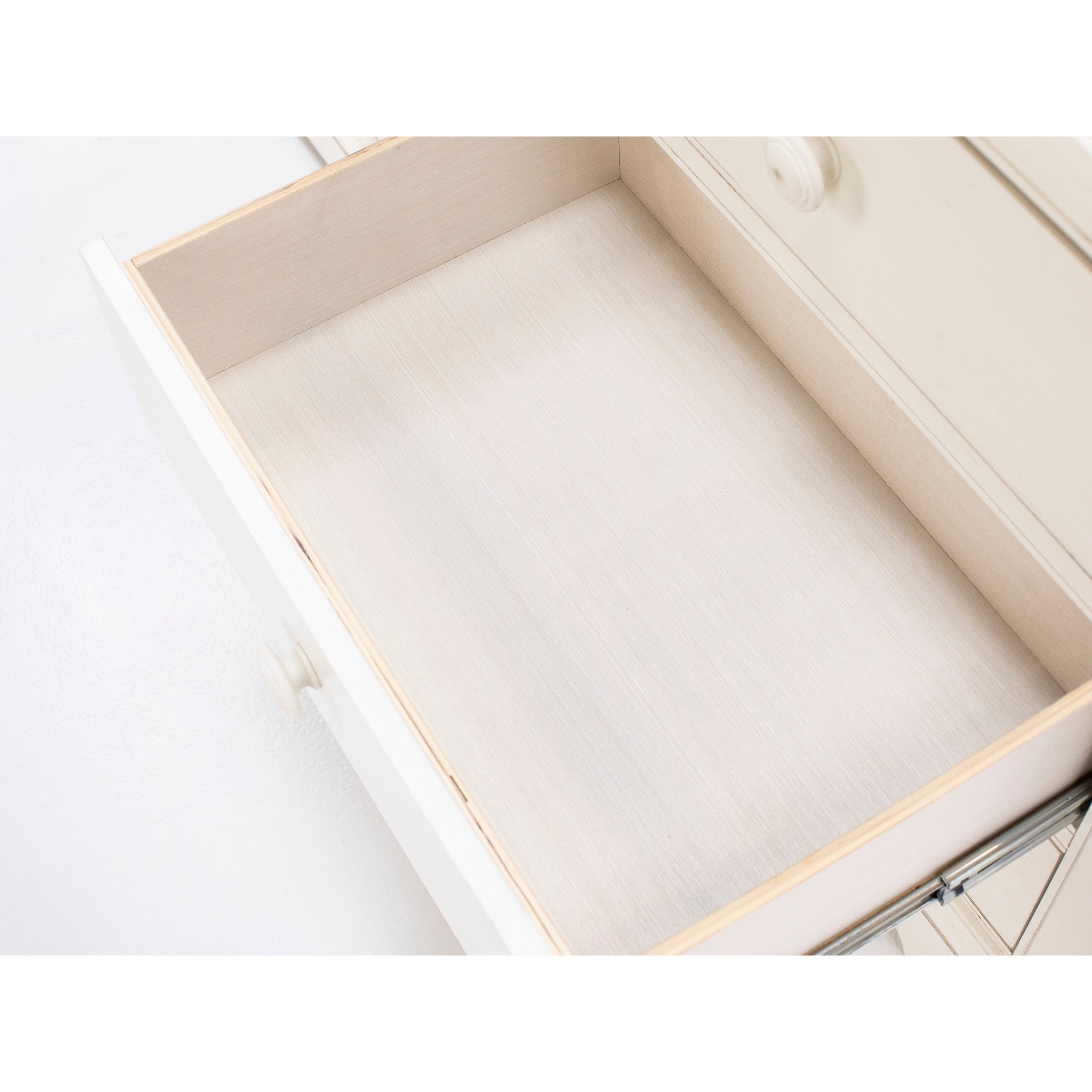 Open, empty white wooden drawer shown from above.