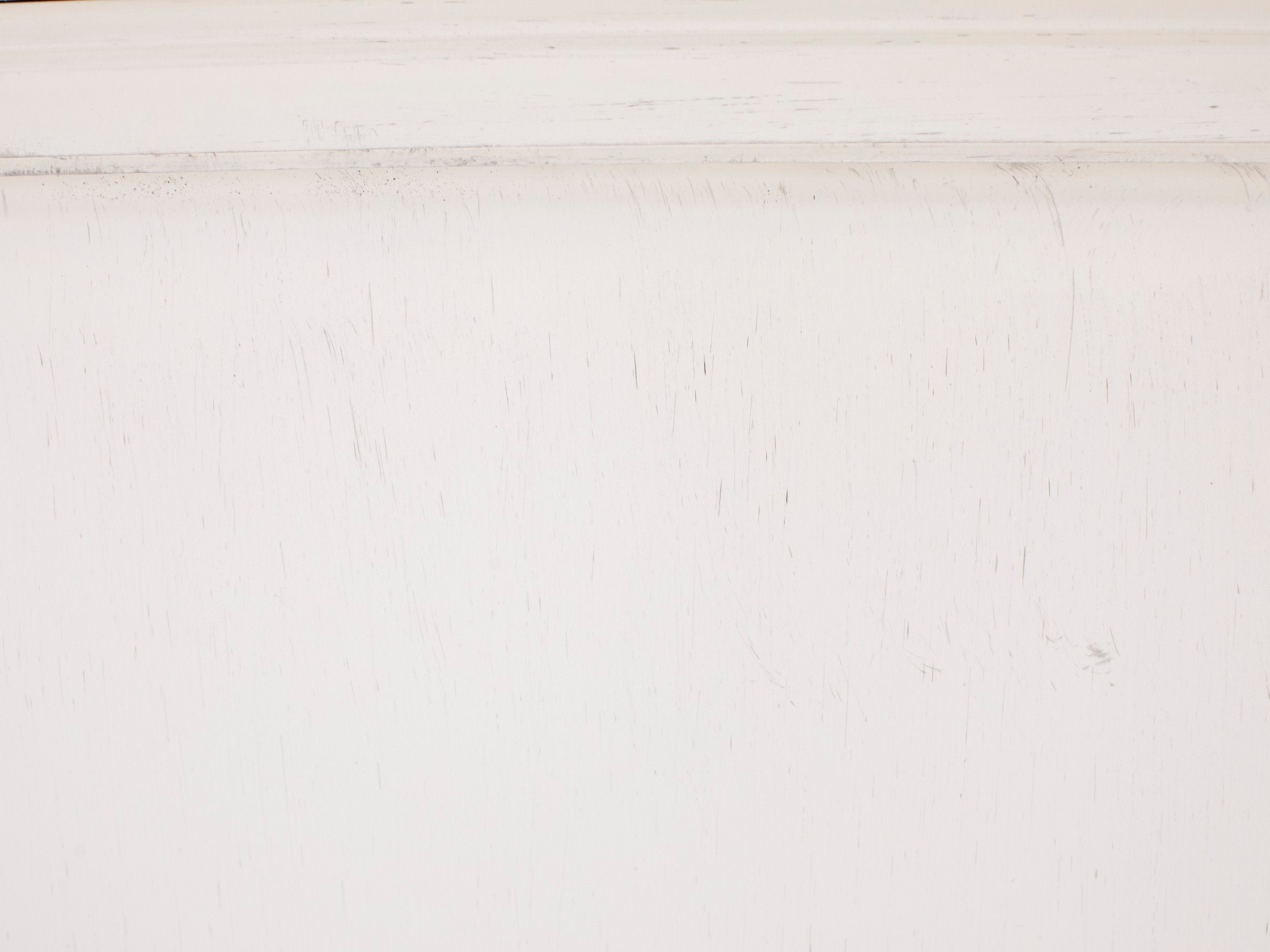 Close up of a white painted wood surface with subtle distress marks.