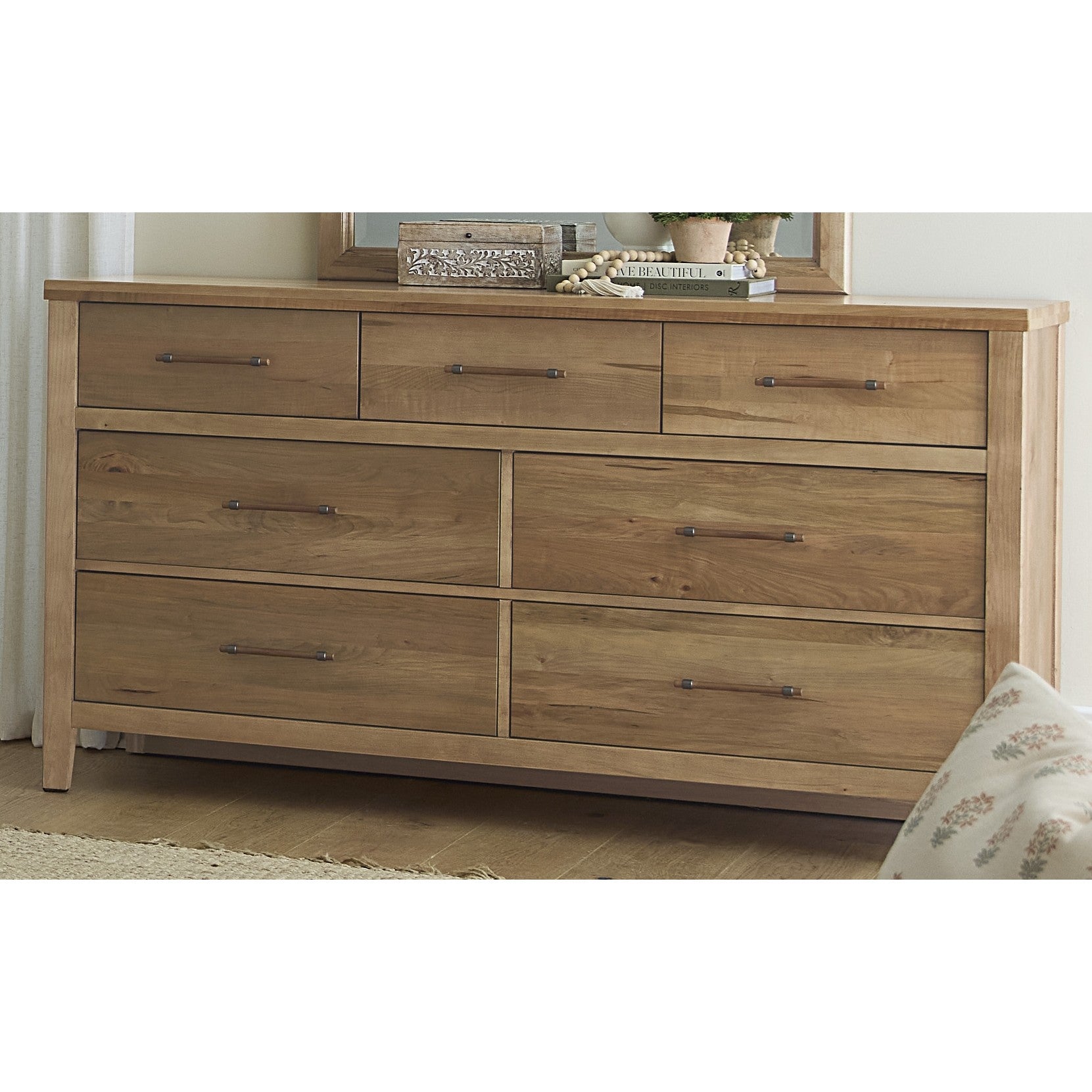 Natural wood dresser with seven drawers and metal handles.