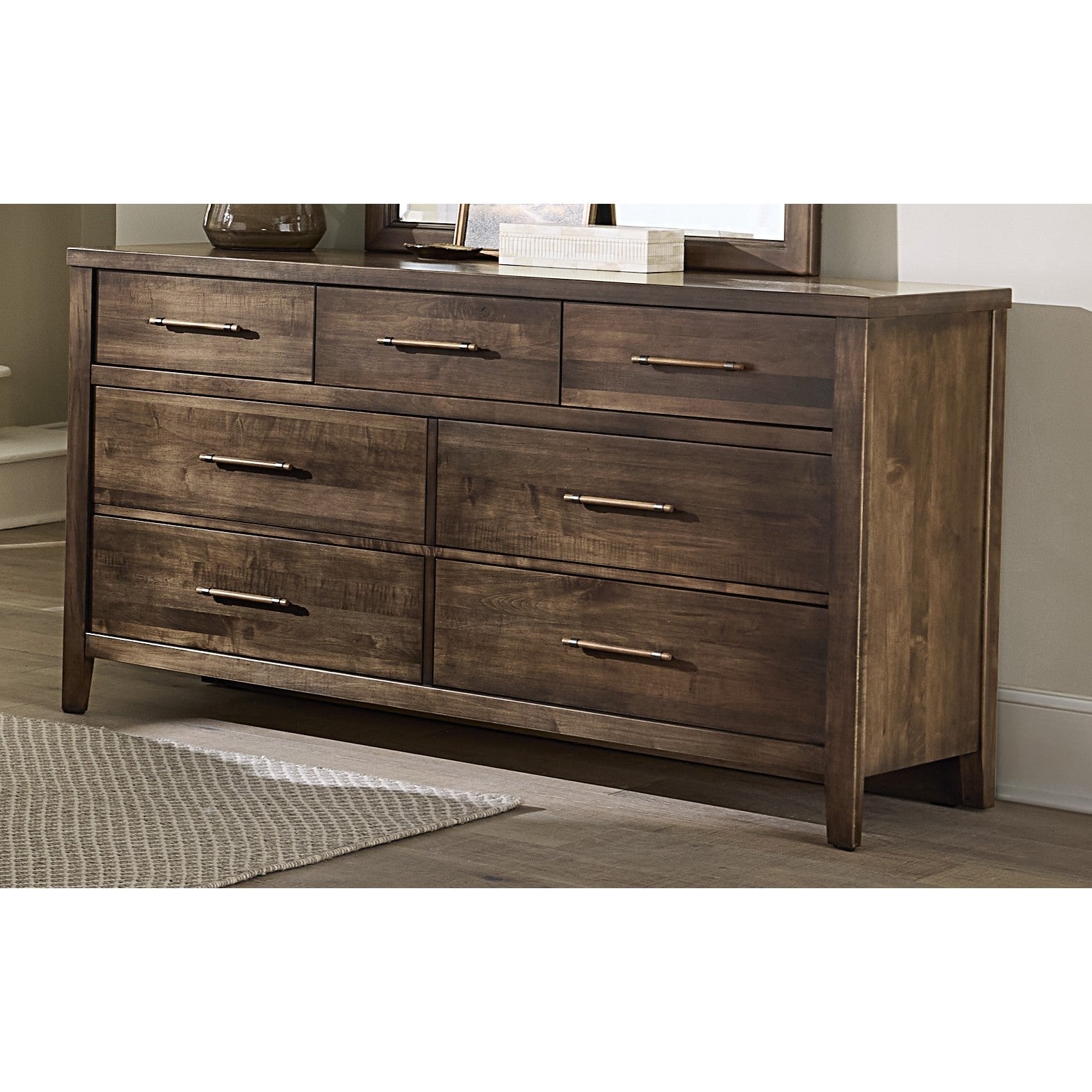 Dark wood dresser with seven drawers and metal handles, shown in a modern bedroom.
