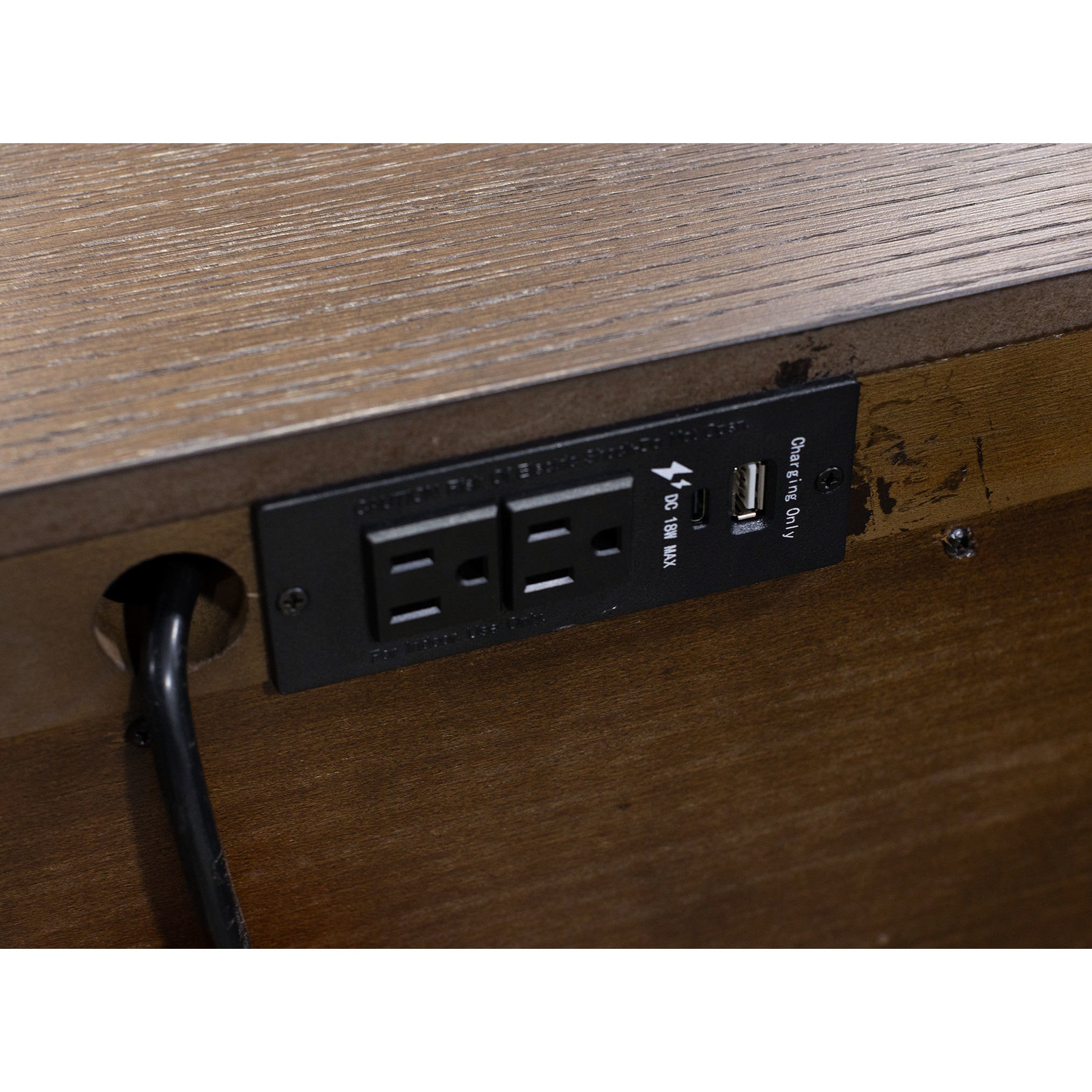 Close-up of built-in power outlet and USB ports on a wooden surface.