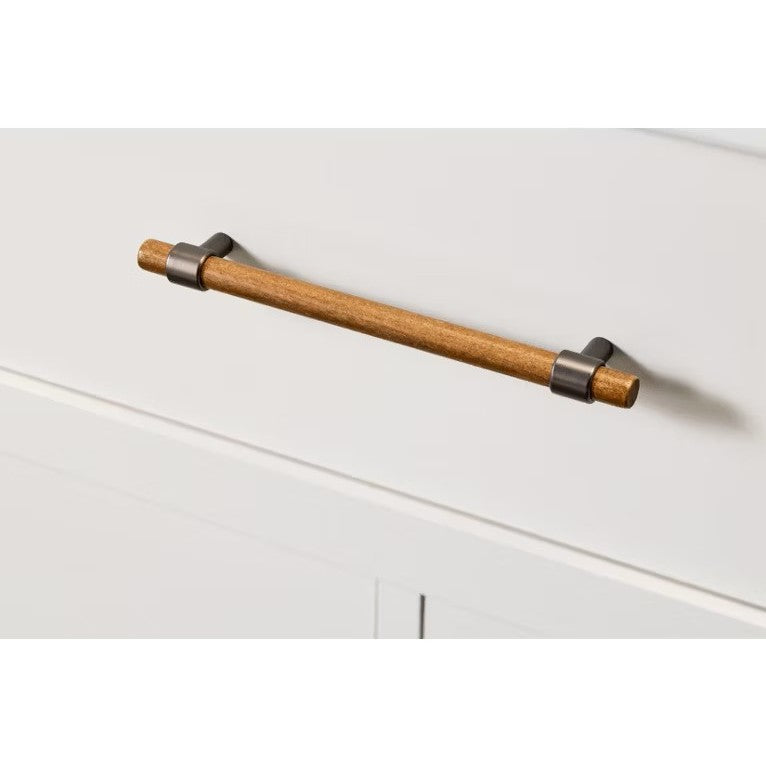 Wood cabinet pull handle with dark metal brackets on a white drawer.