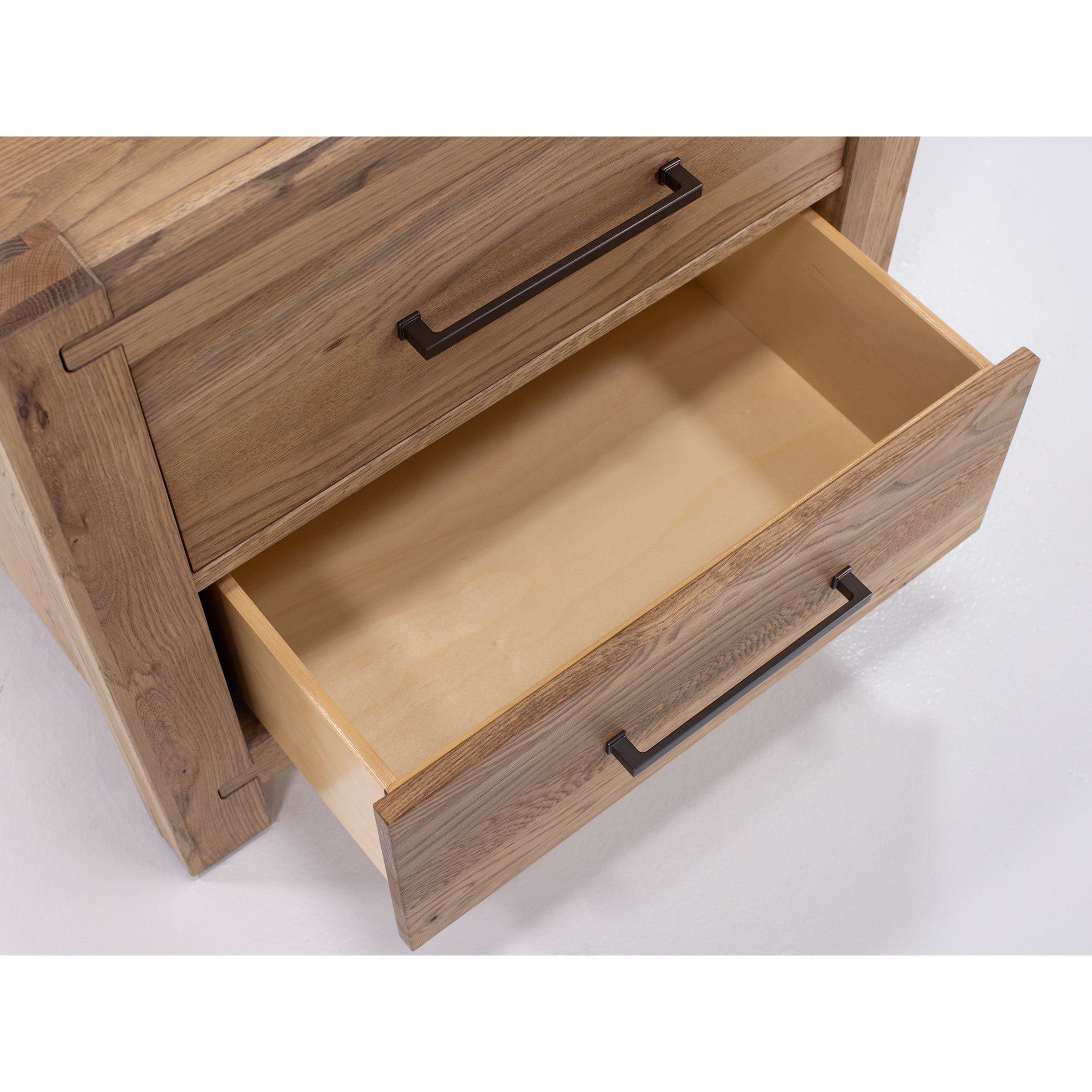 Open wooden drawer in a dresser with metal handle, shown from above.