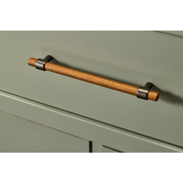 Wooden drawer handle with metal brackets on a green cabinet.