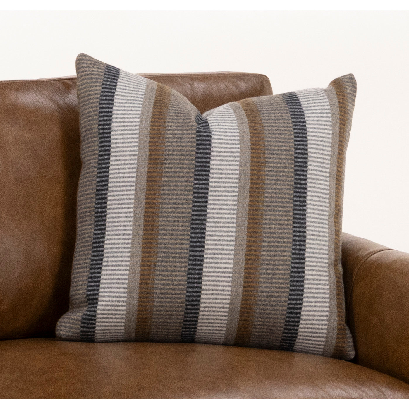 Striped pillow with neutral colors on a brown leather chair.