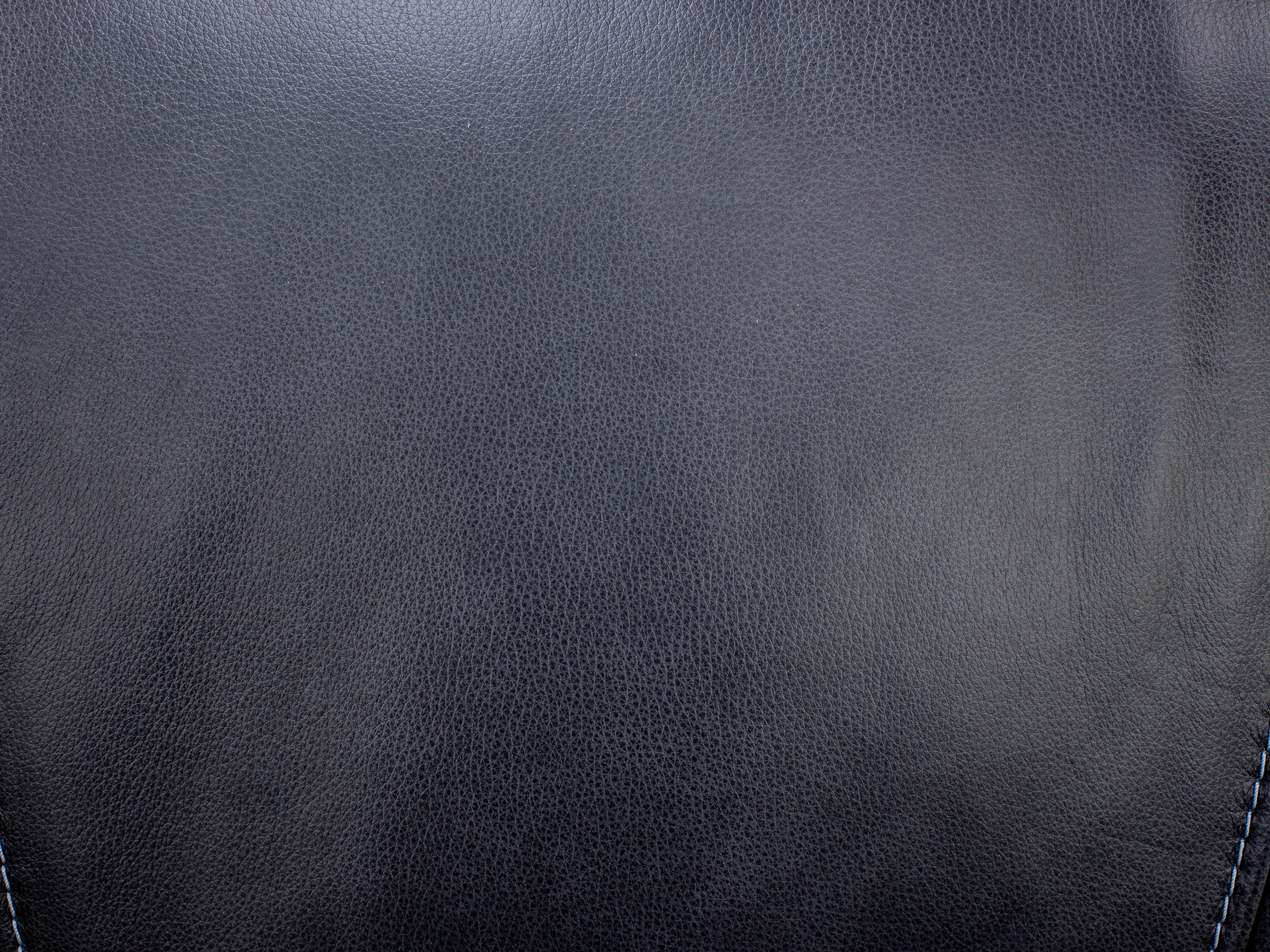 Close-up of black leather texture with visible stitching.