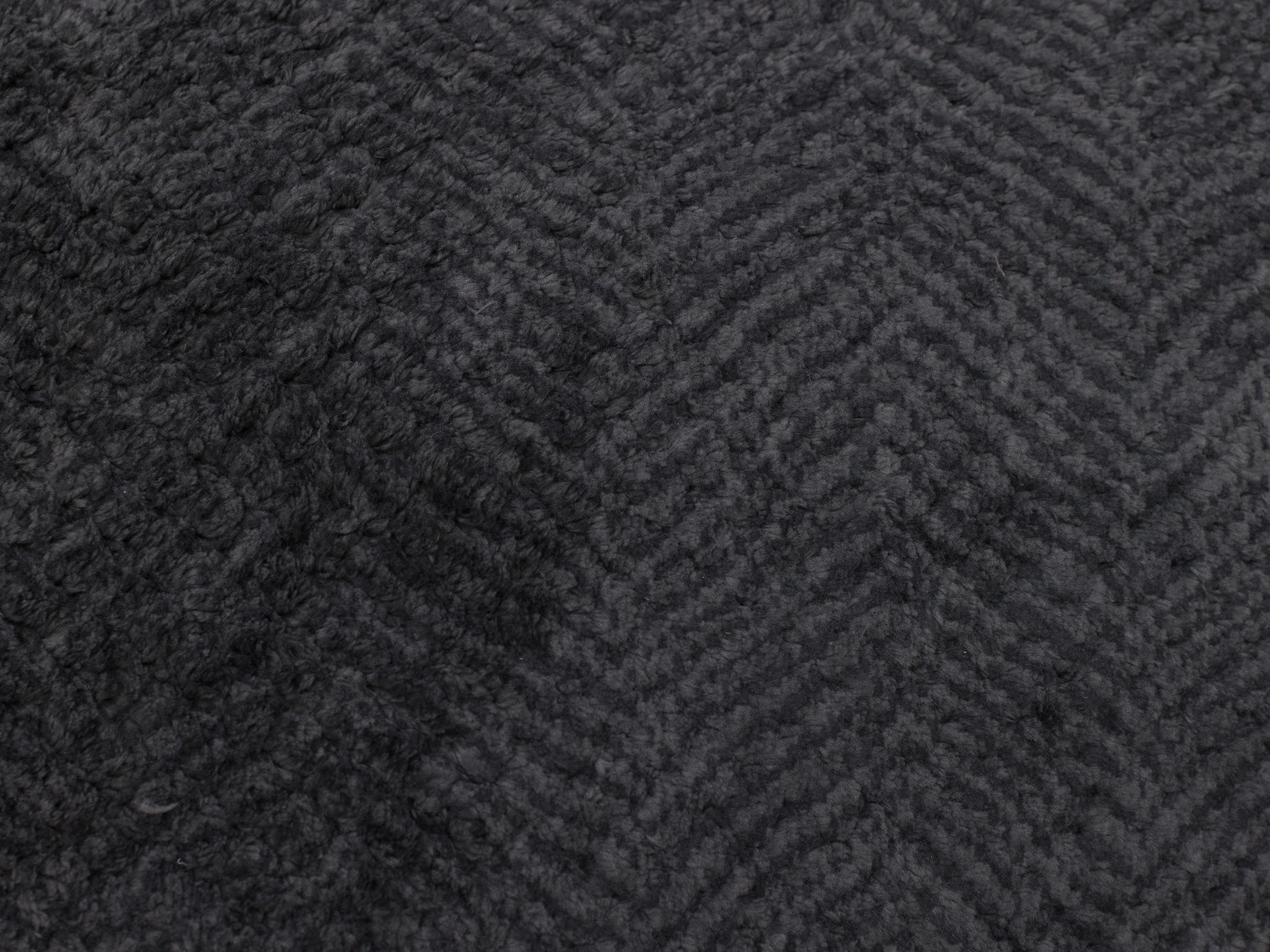 Dark gray textured fabric with a subtle chevron pattern.