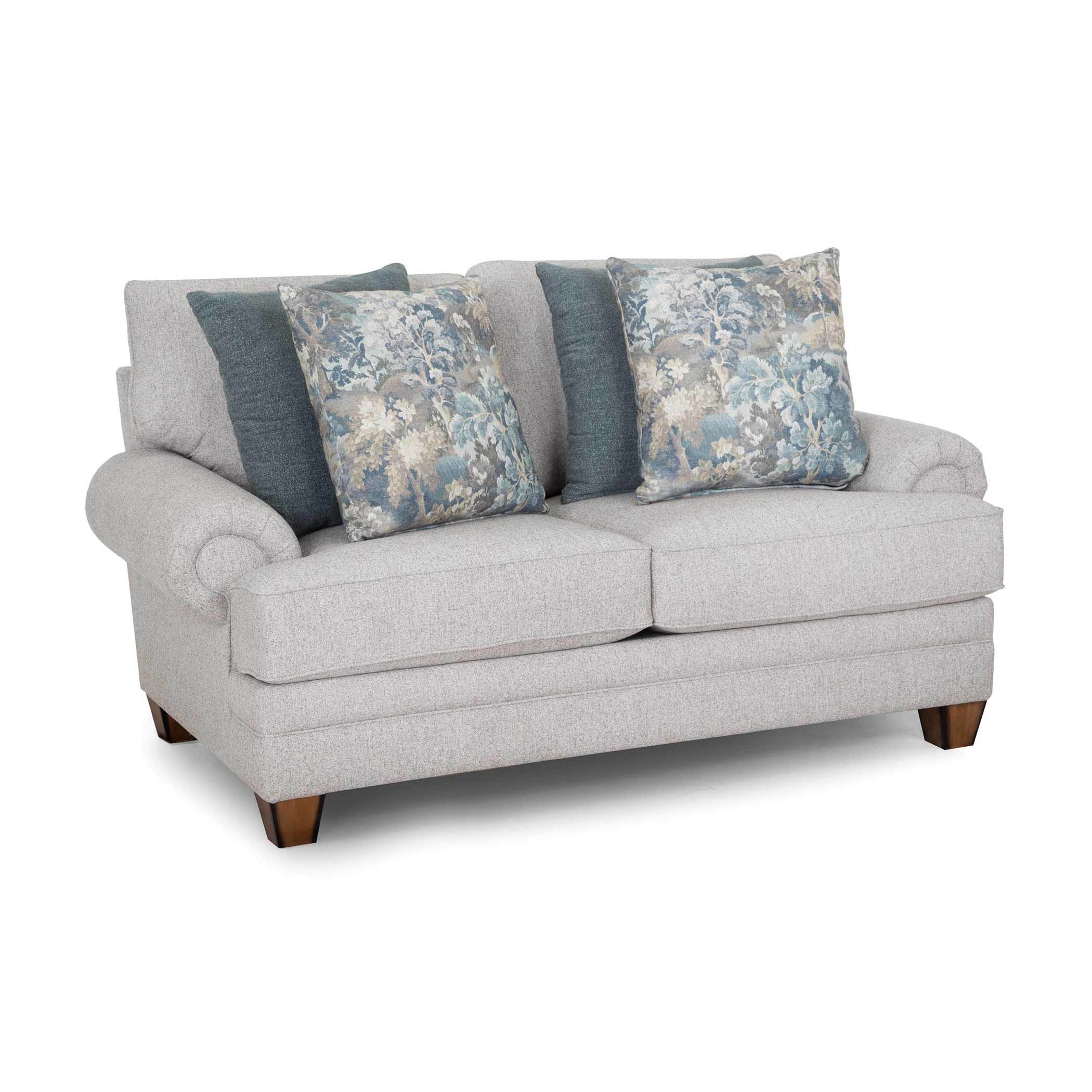 Light gray loveseat with four blue and floral pillows, shown on a white background.