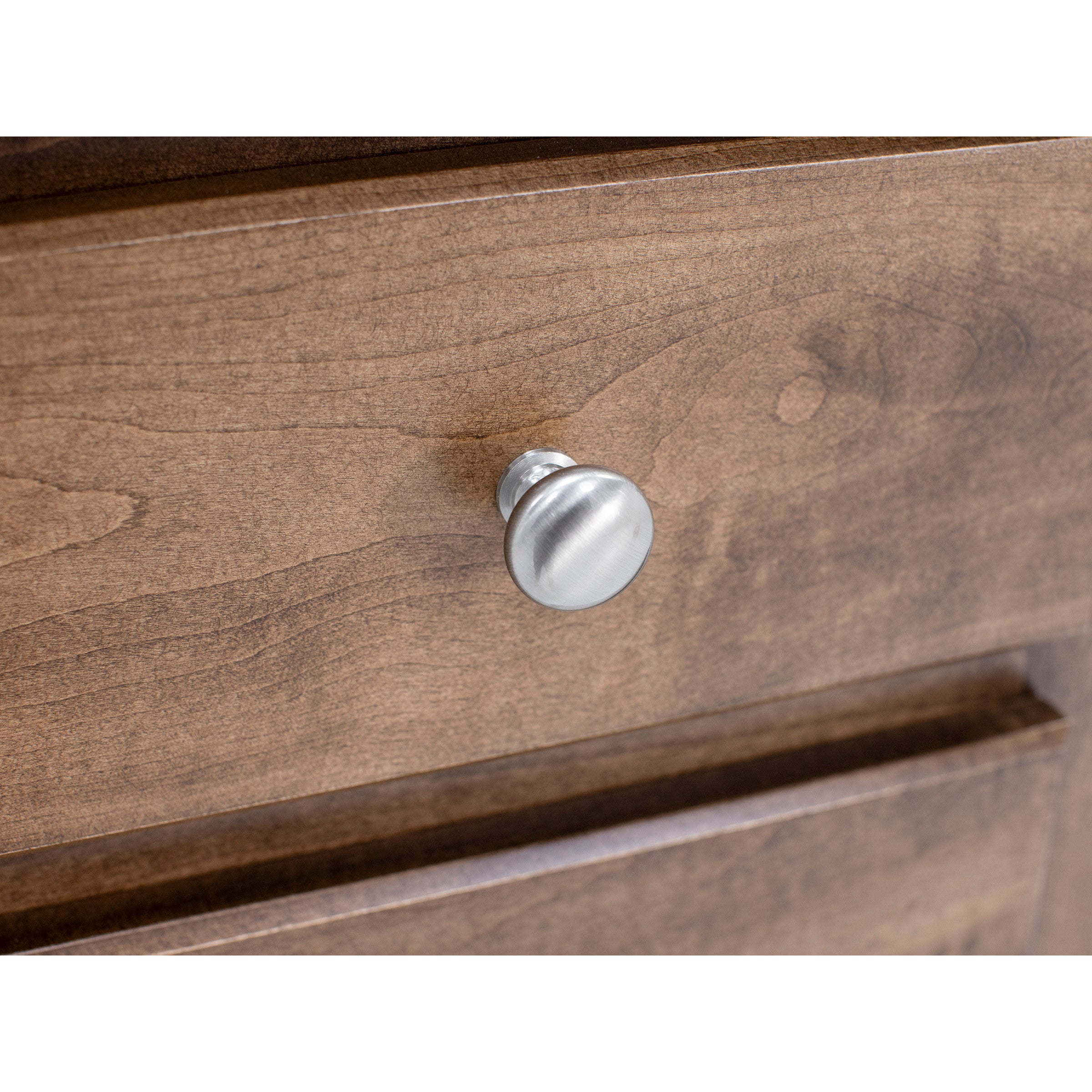 Close-up of a brushed metal knob on a wood drawer.