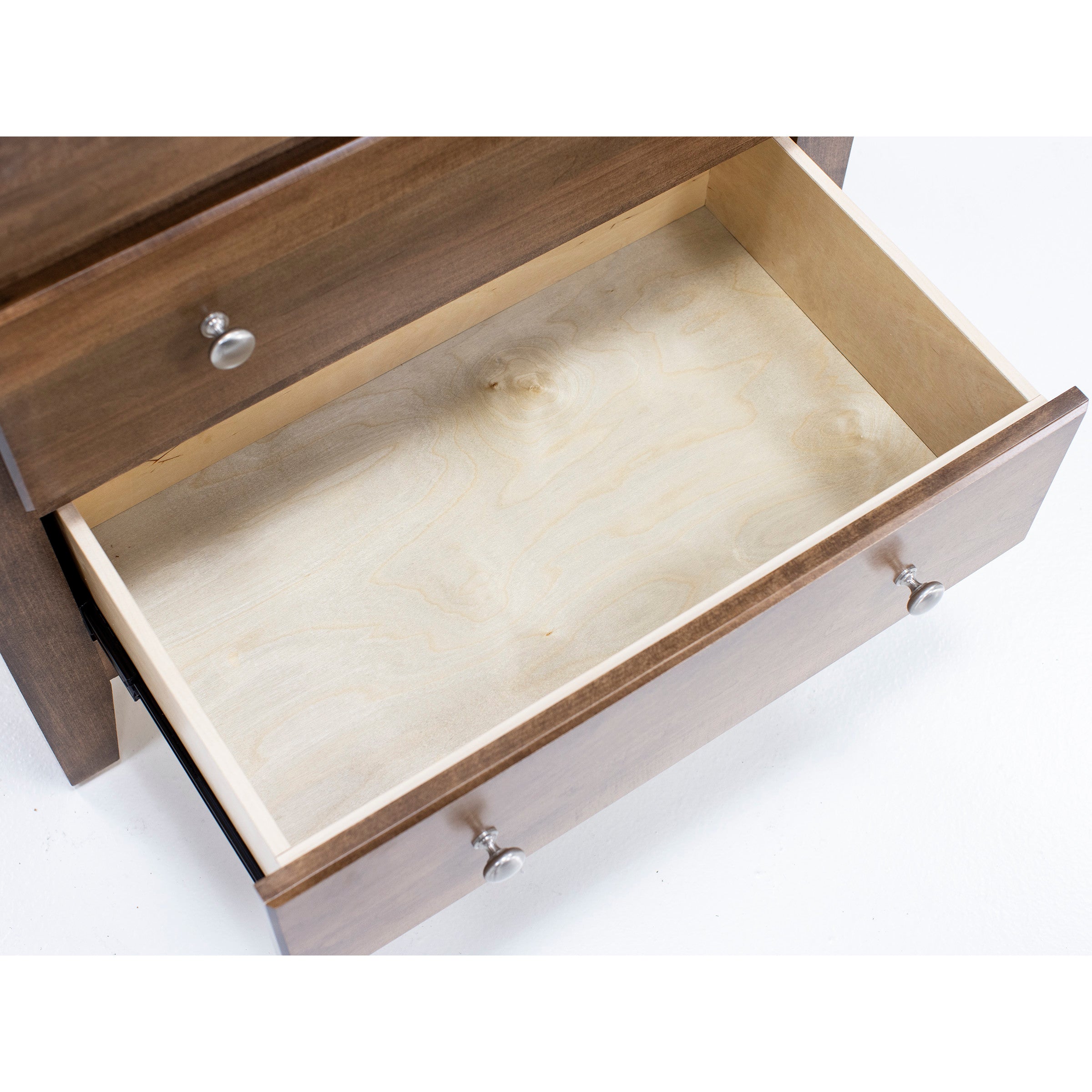 Open empty wooden drawer with silver knobs.