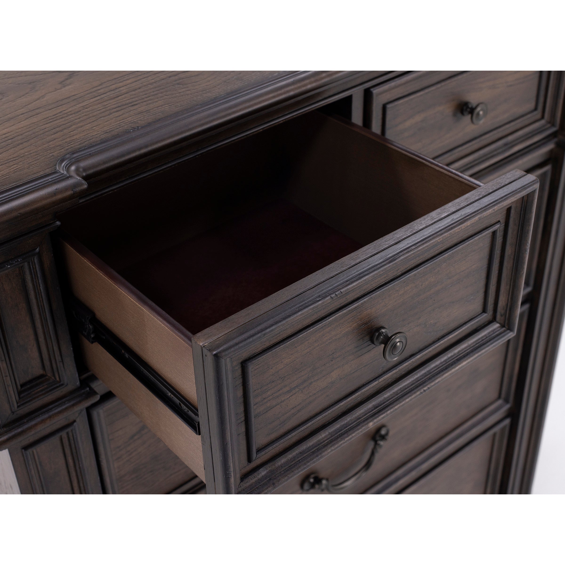 Open wood desk drawer with metal handle, showing interior.