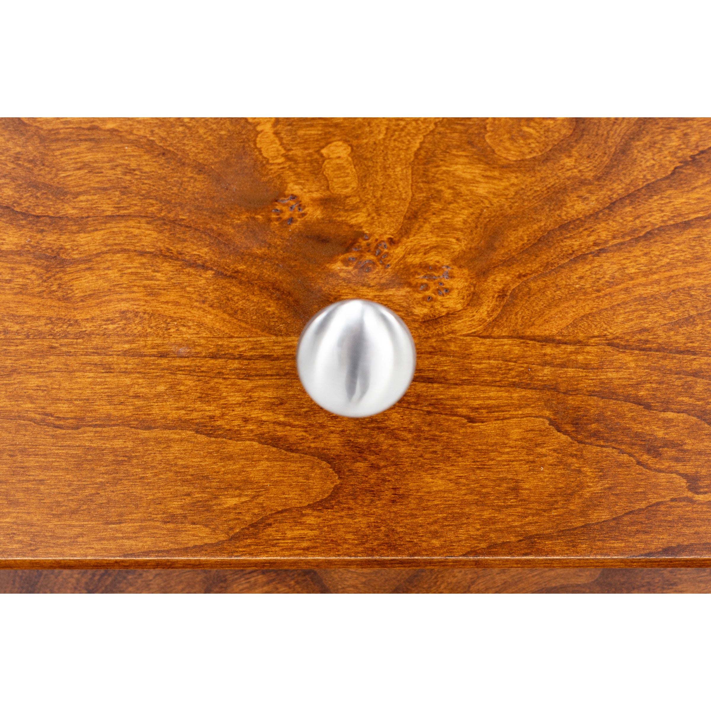 Brushed nickel knob on wooden drawer front.