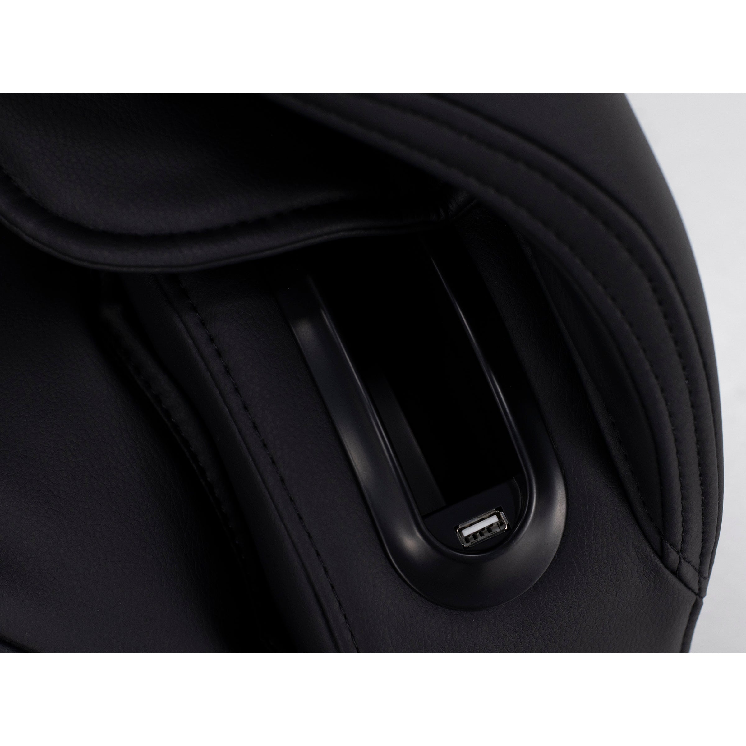 Close-up of a built-in USB port on a dark leather surface, likely part of a chair or bag.