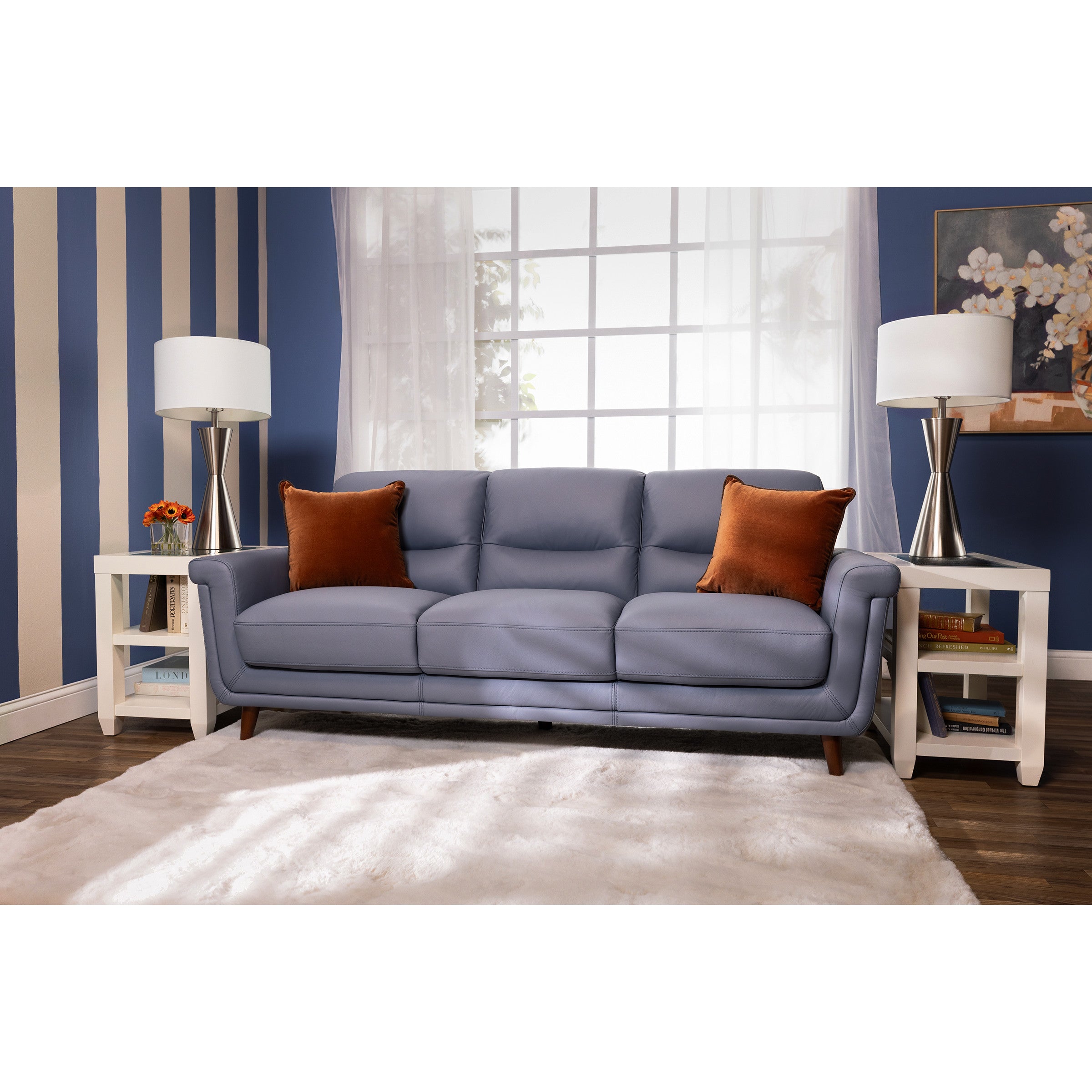 Modern blue sofa with orange pillows in a bright living room setting.