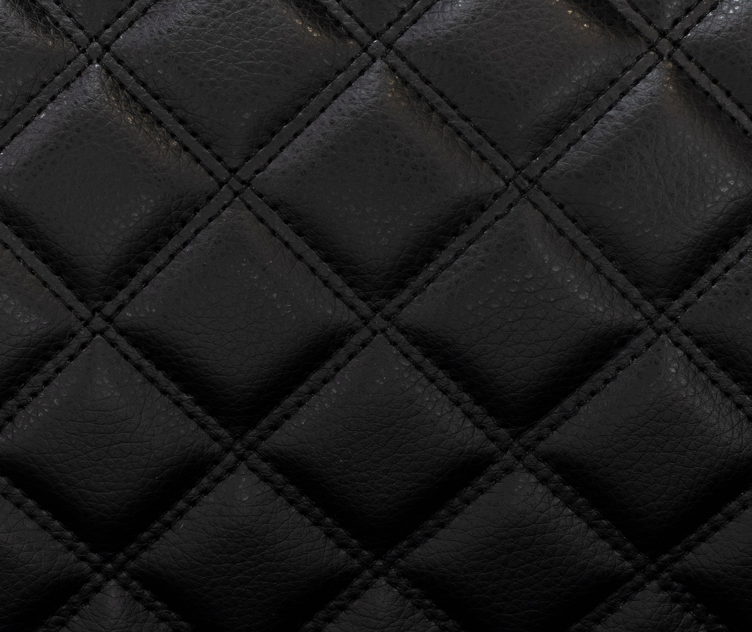 Close-up of black quilted leather texture, showing diamond stitching pattern.