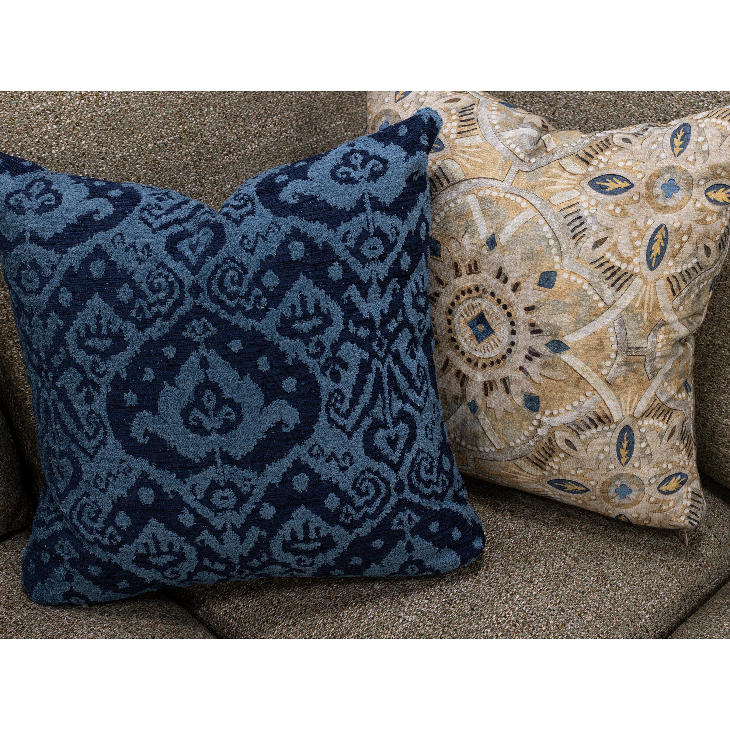 Two decorative throw pillows with blue and tan patterns on a brown fabric sofa.