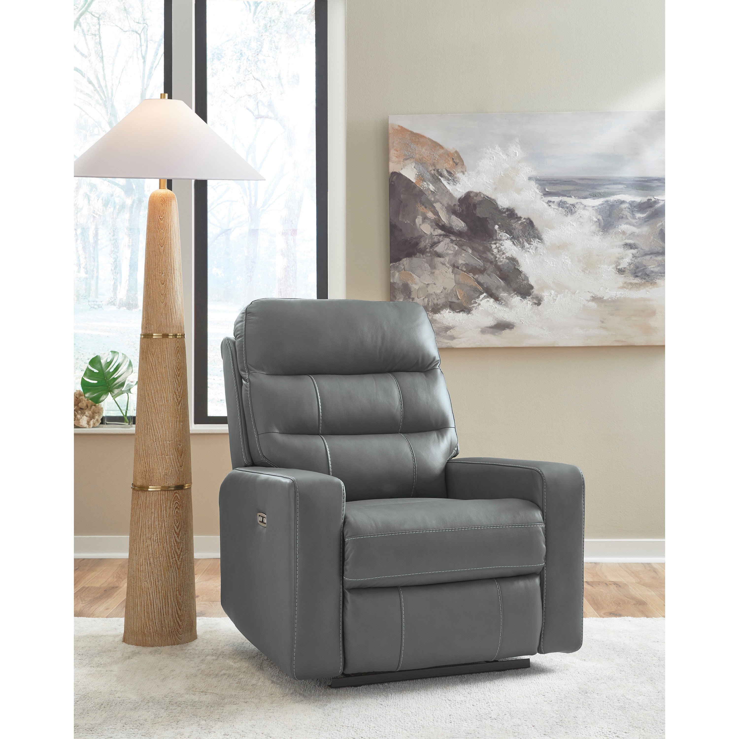 Gray leather recliner chair next to a tall lamp in a modern living room.