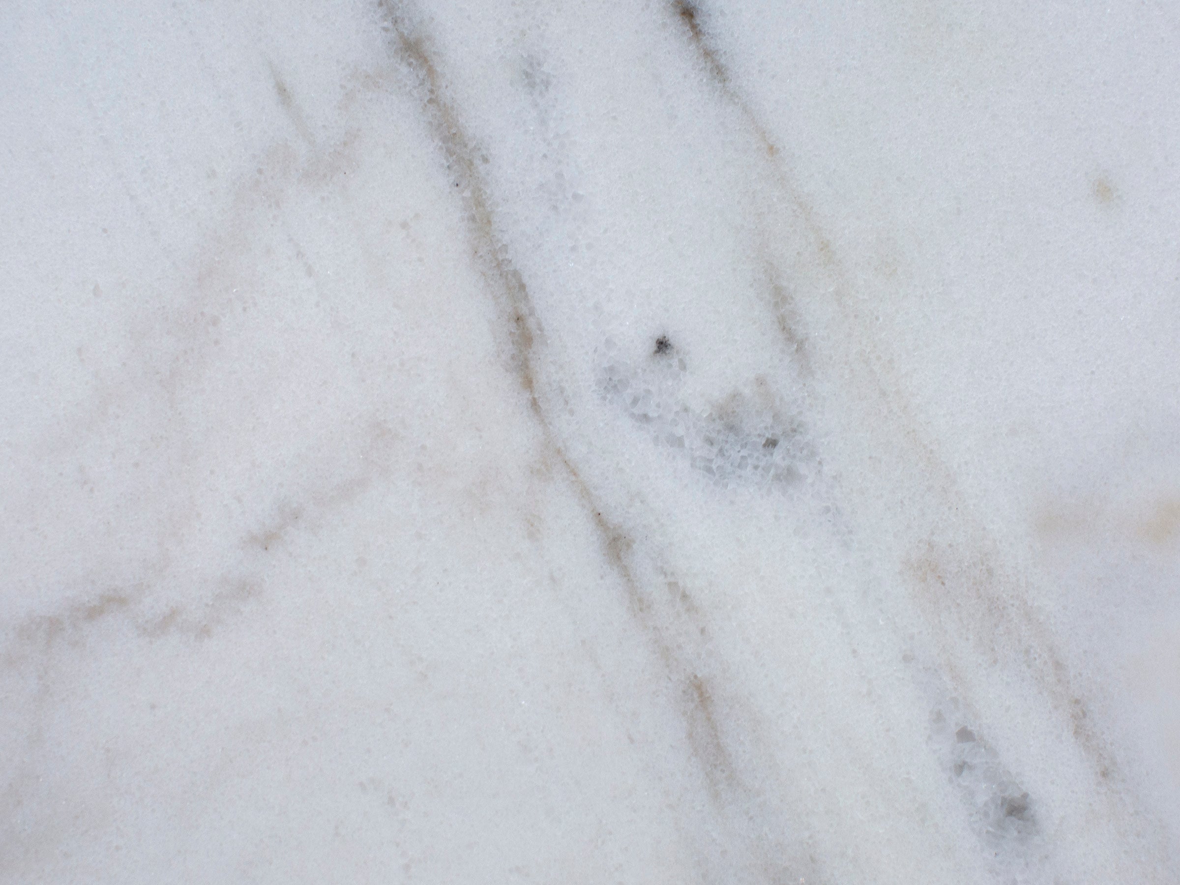 White marble surface with subtle grey veins and natural texture.