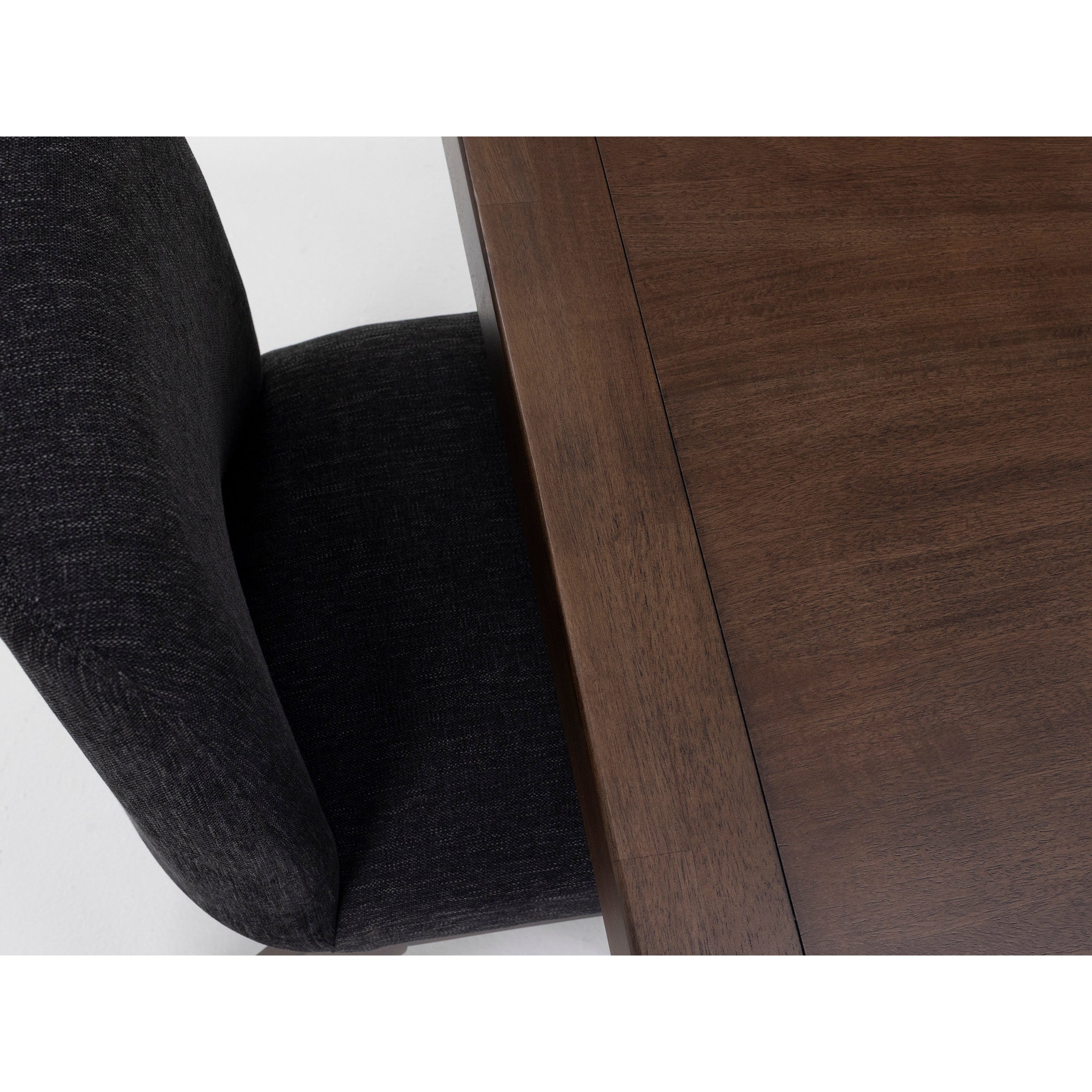 Close-up of a dark upholstered chair next to a wooden table.