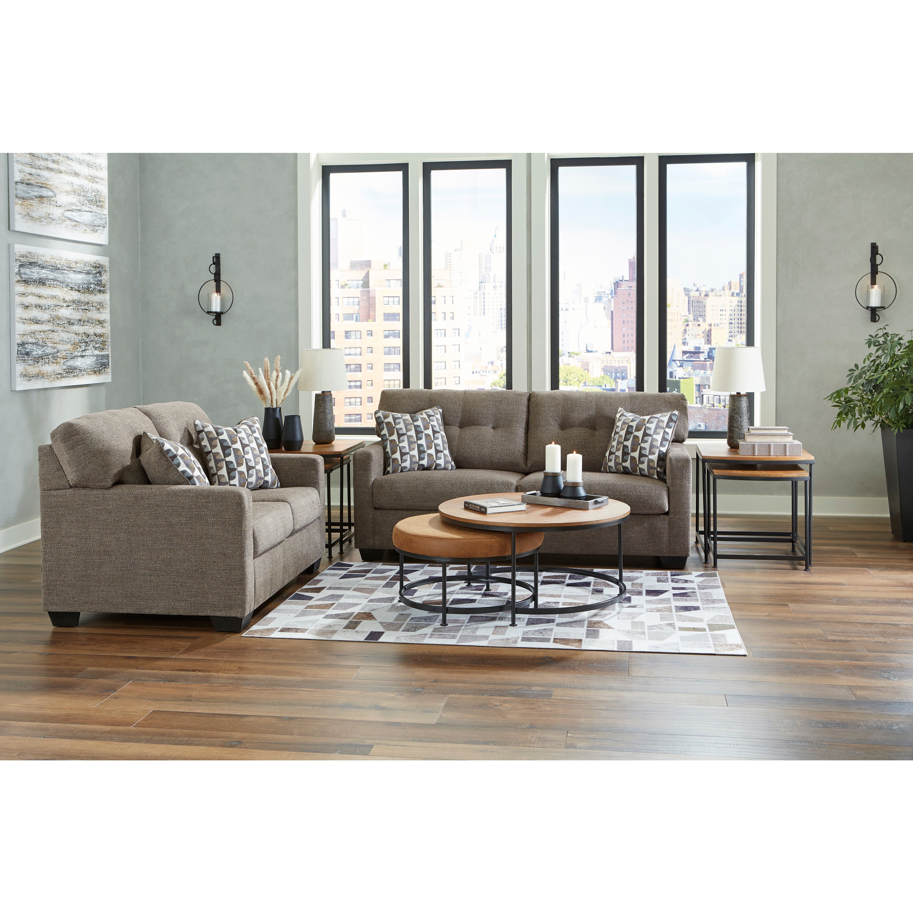 Modern living room with two gray sofas, patterned pillows, round coffee tables, and city view windows.