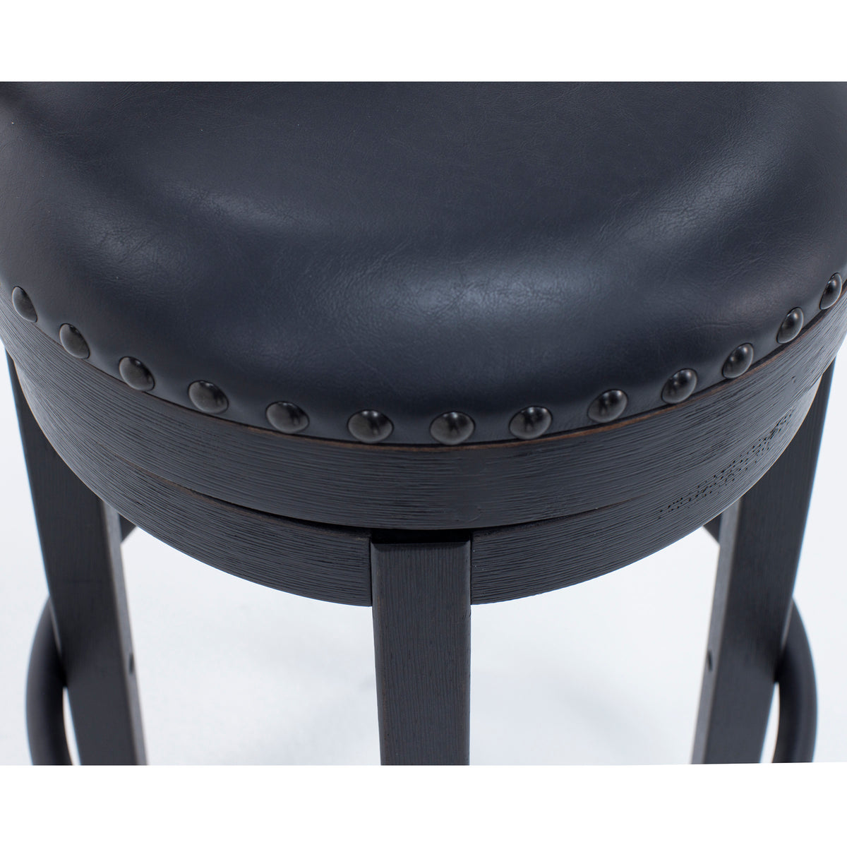 Close-up of a black leather upholstered stool seat with studded trim.