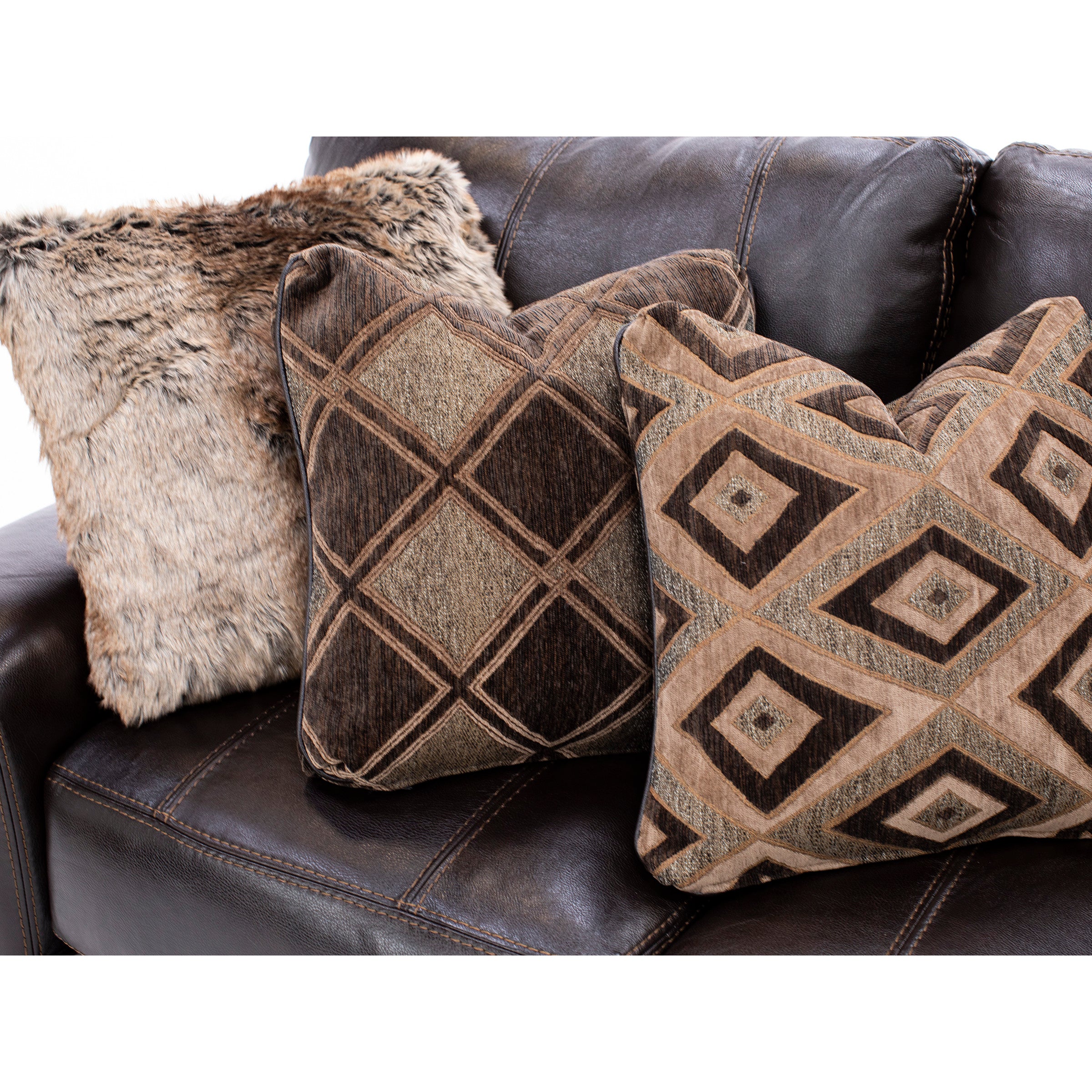 Three decorative pillows on a dark brown leather sofa, featuring various textures and geometric patterns.