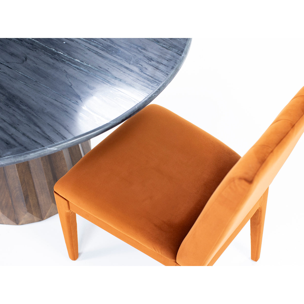 Top view of an orange upholstered chair next to a round dark marble table.