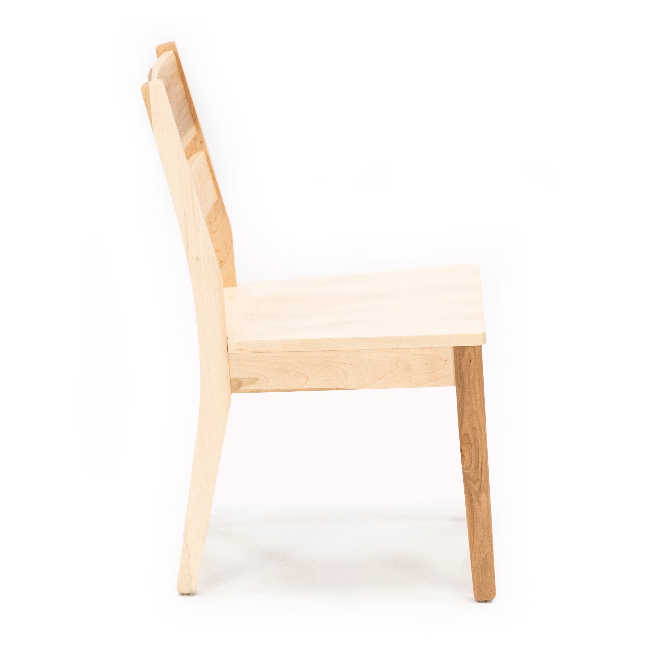 Side view of a simple, light-colored wooden chair on a white background.