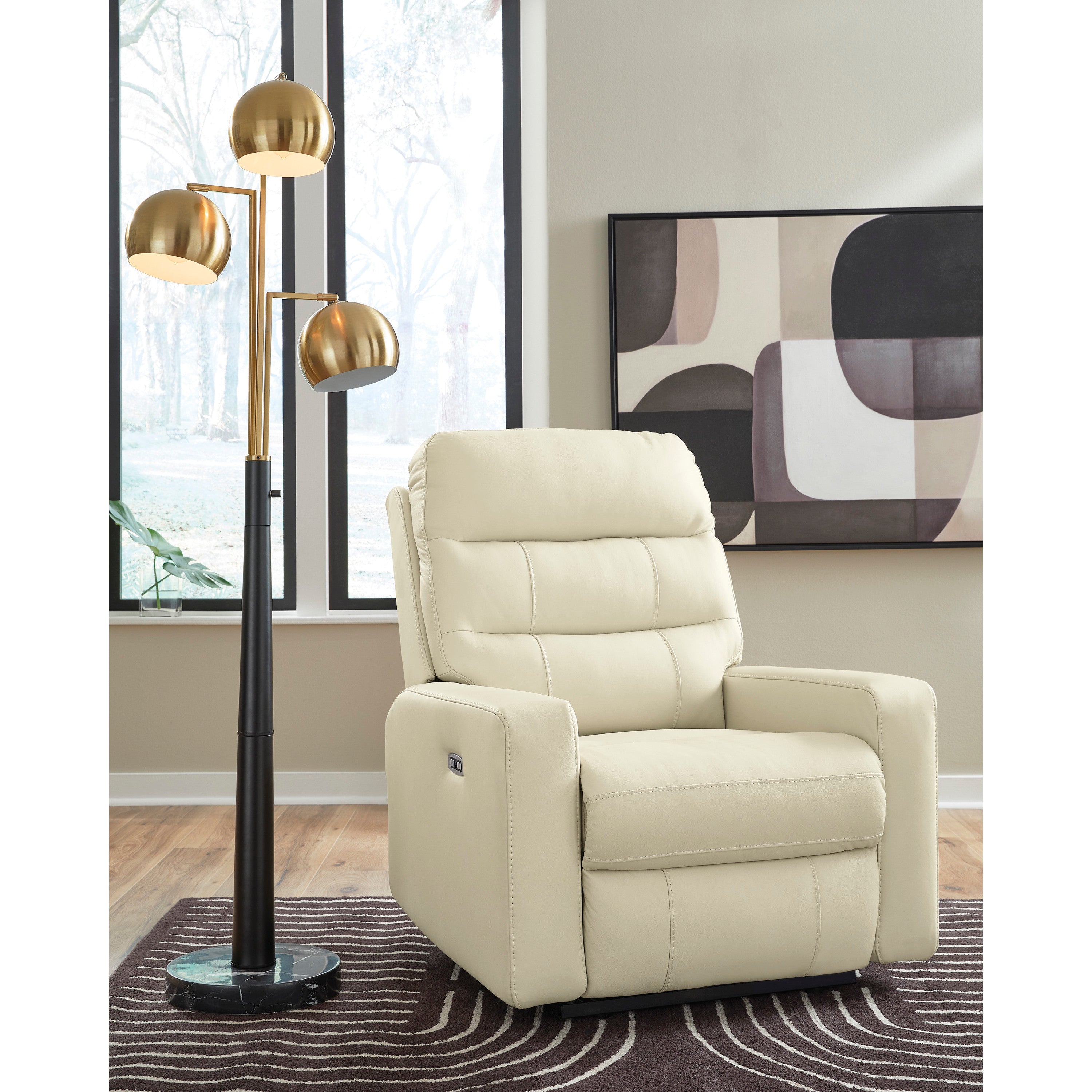 Modern cream recliner in a living room with a gold floor lamp and abstract artwork.