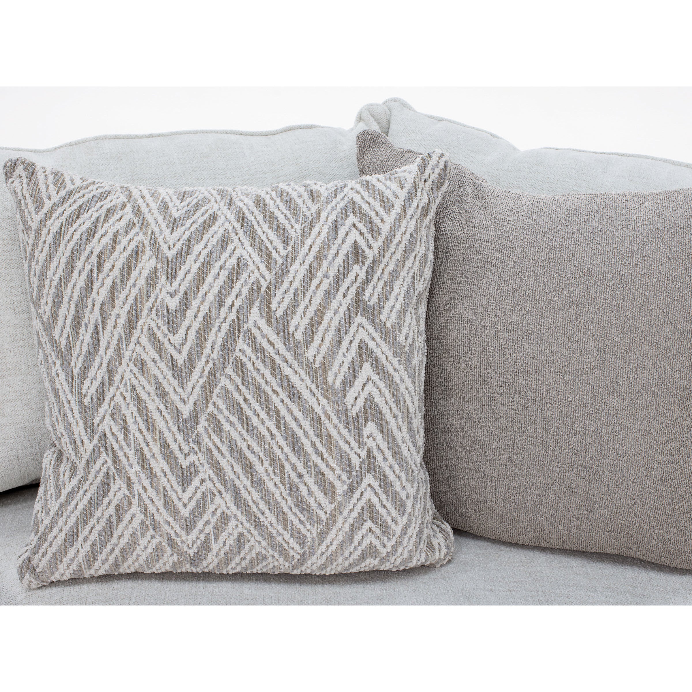 Two decorative throw pillows on a light-colored sofa, one with a geometric pattern.