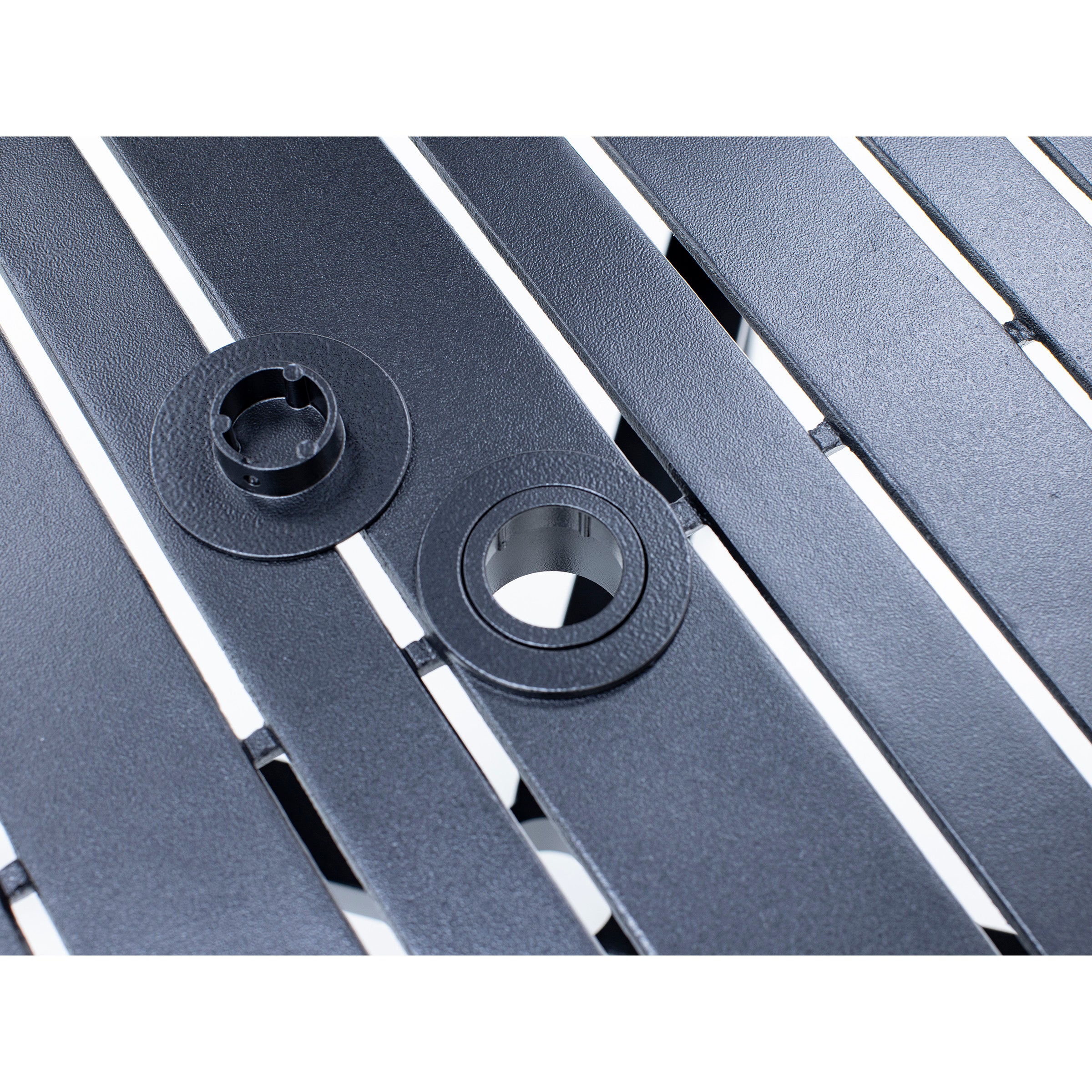 Close-up of a black slatted table with two different size umbrella holes.