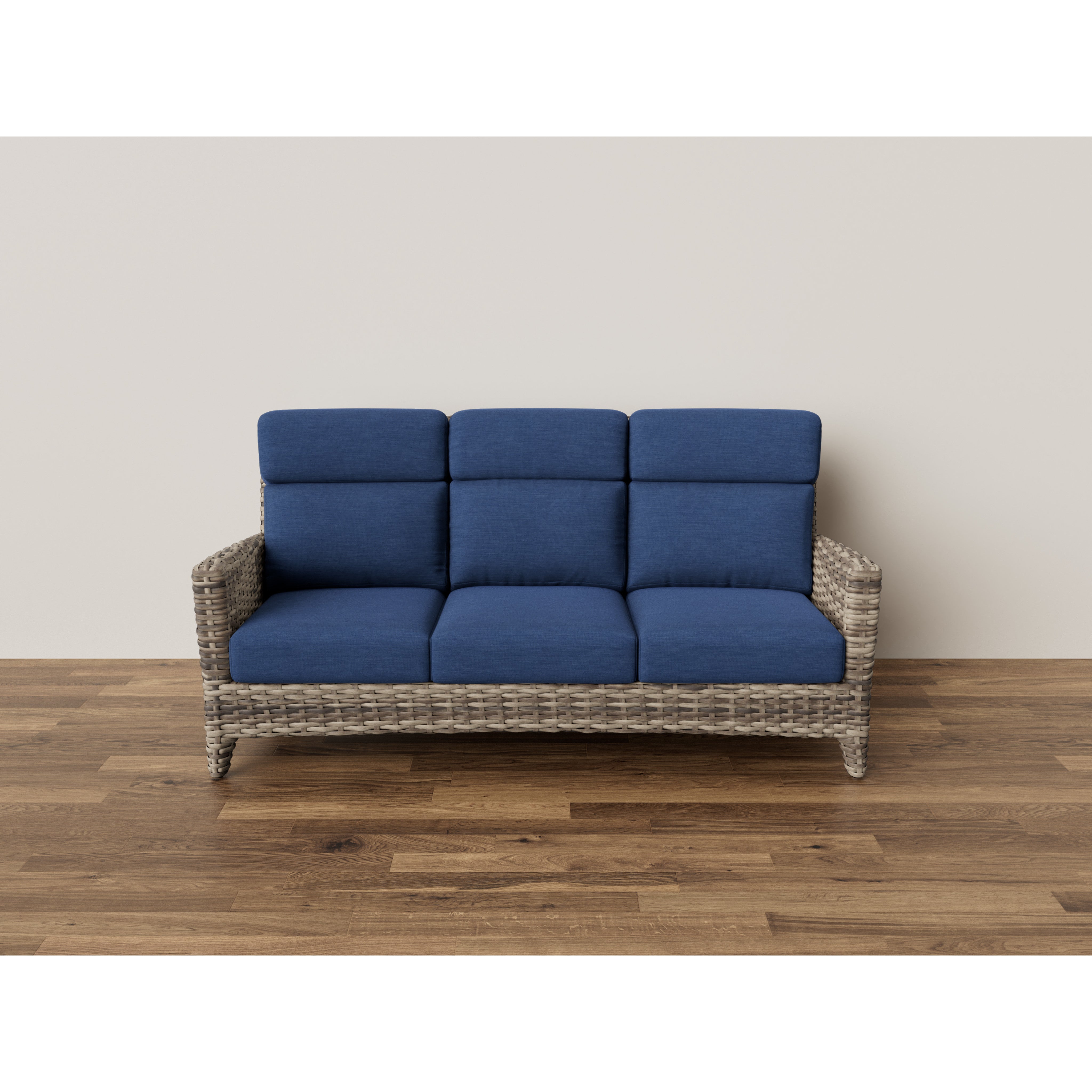 Wicker sofa with blue cushions on wood floor against plain wall.