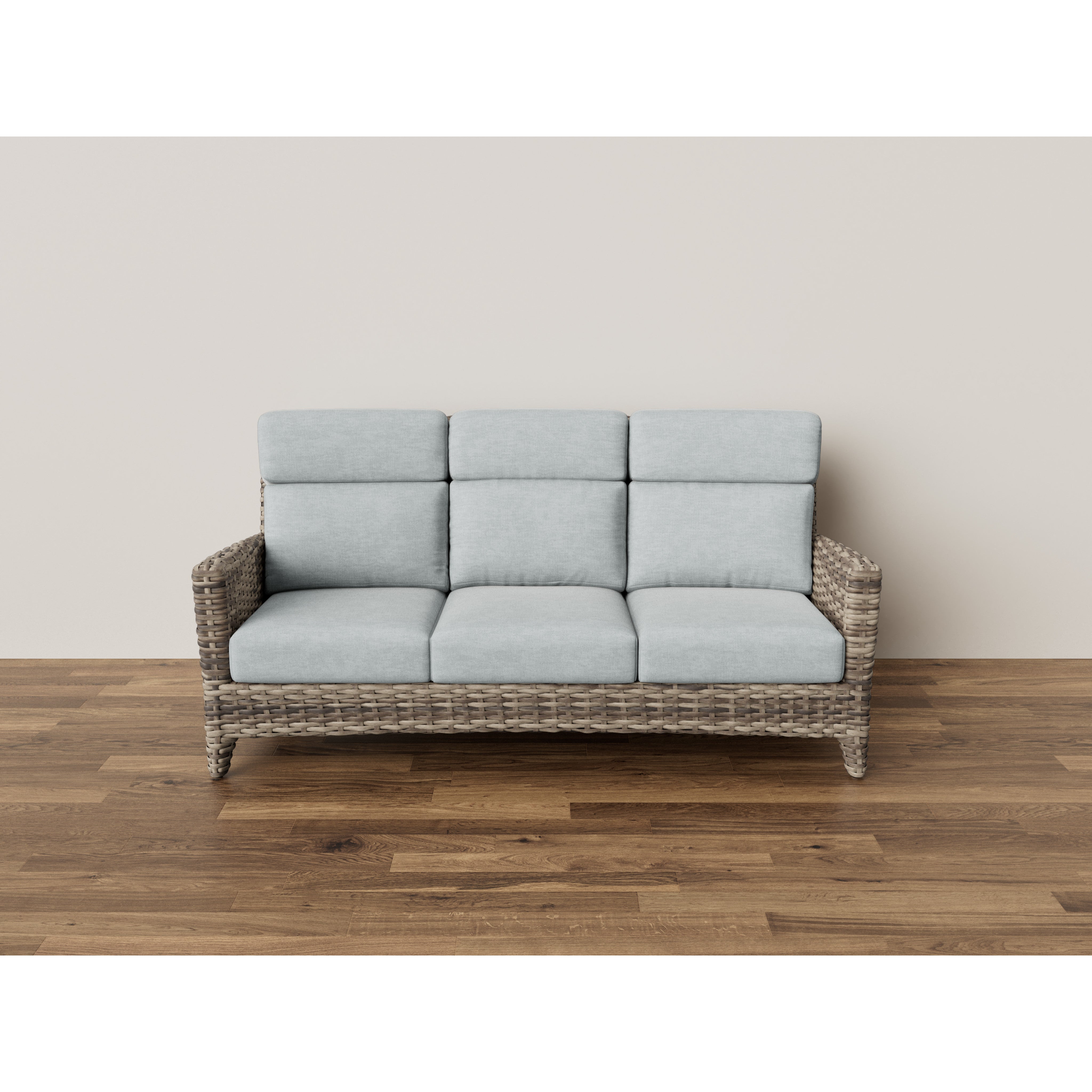 Woven rattan three-seat sofa with light gray cushions on wood floor.