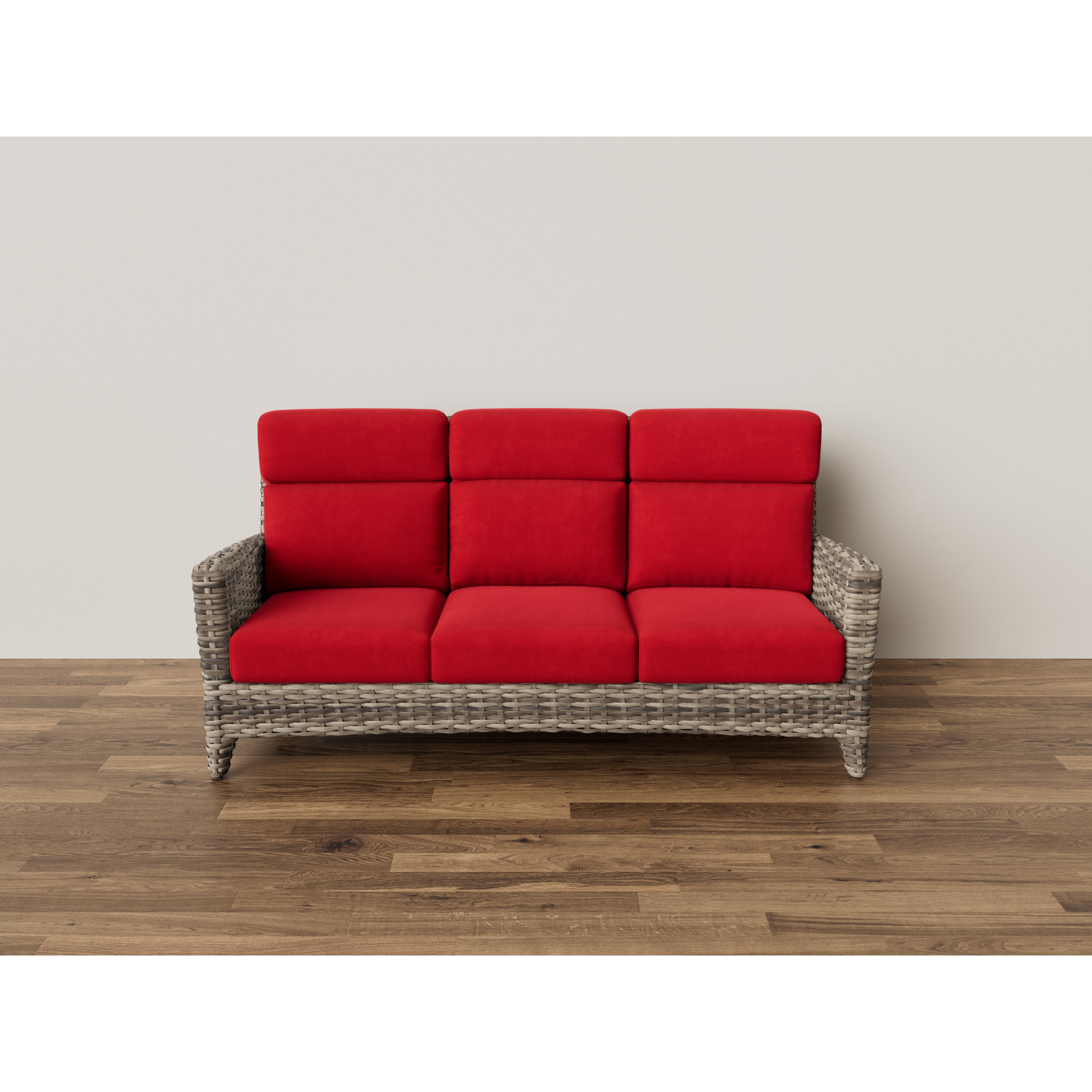 Wicker sofa with vibrant red cushions on wood floor, against a plain wall.