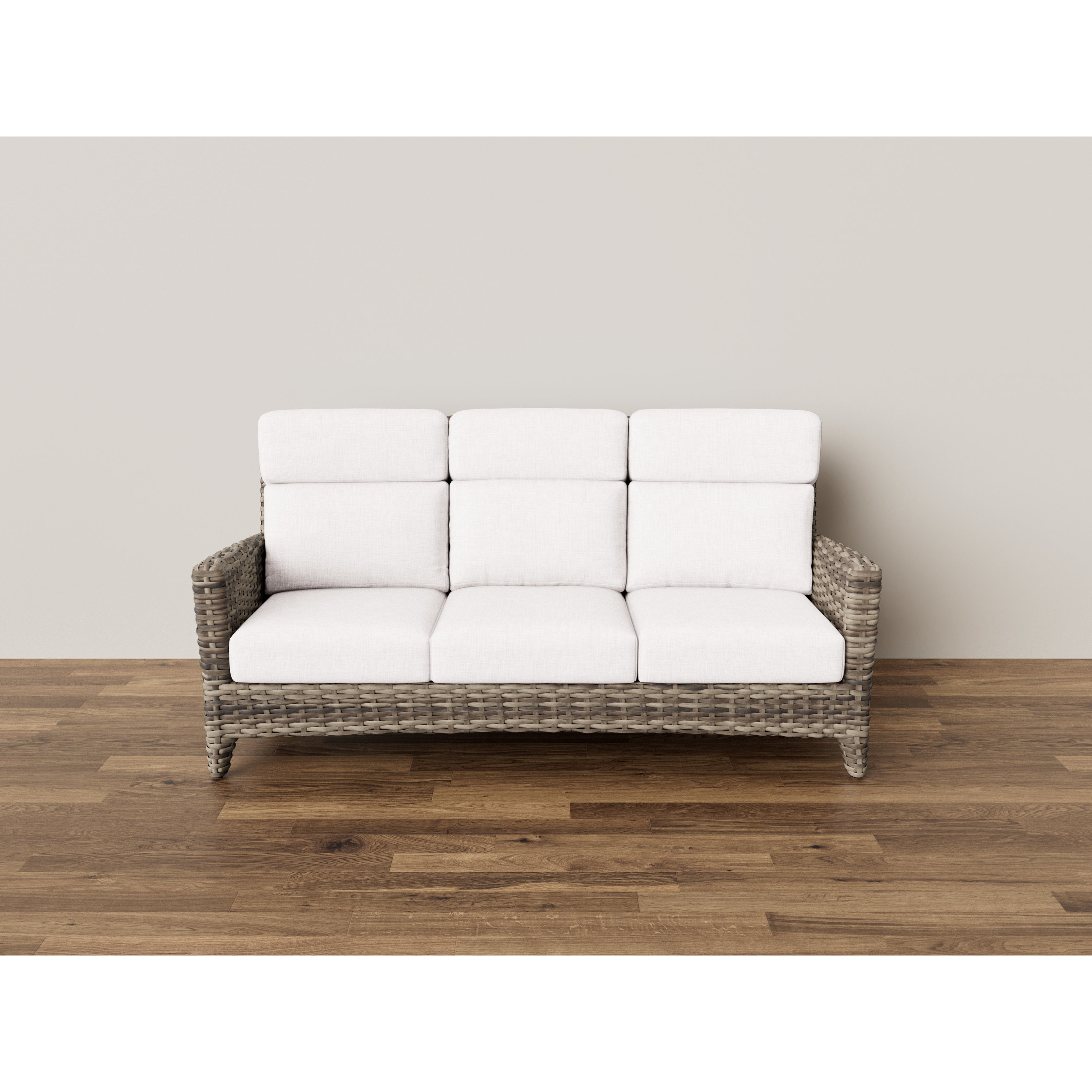 Three-seat wicker sofa with white cushions on a wood floor against a plain wall.