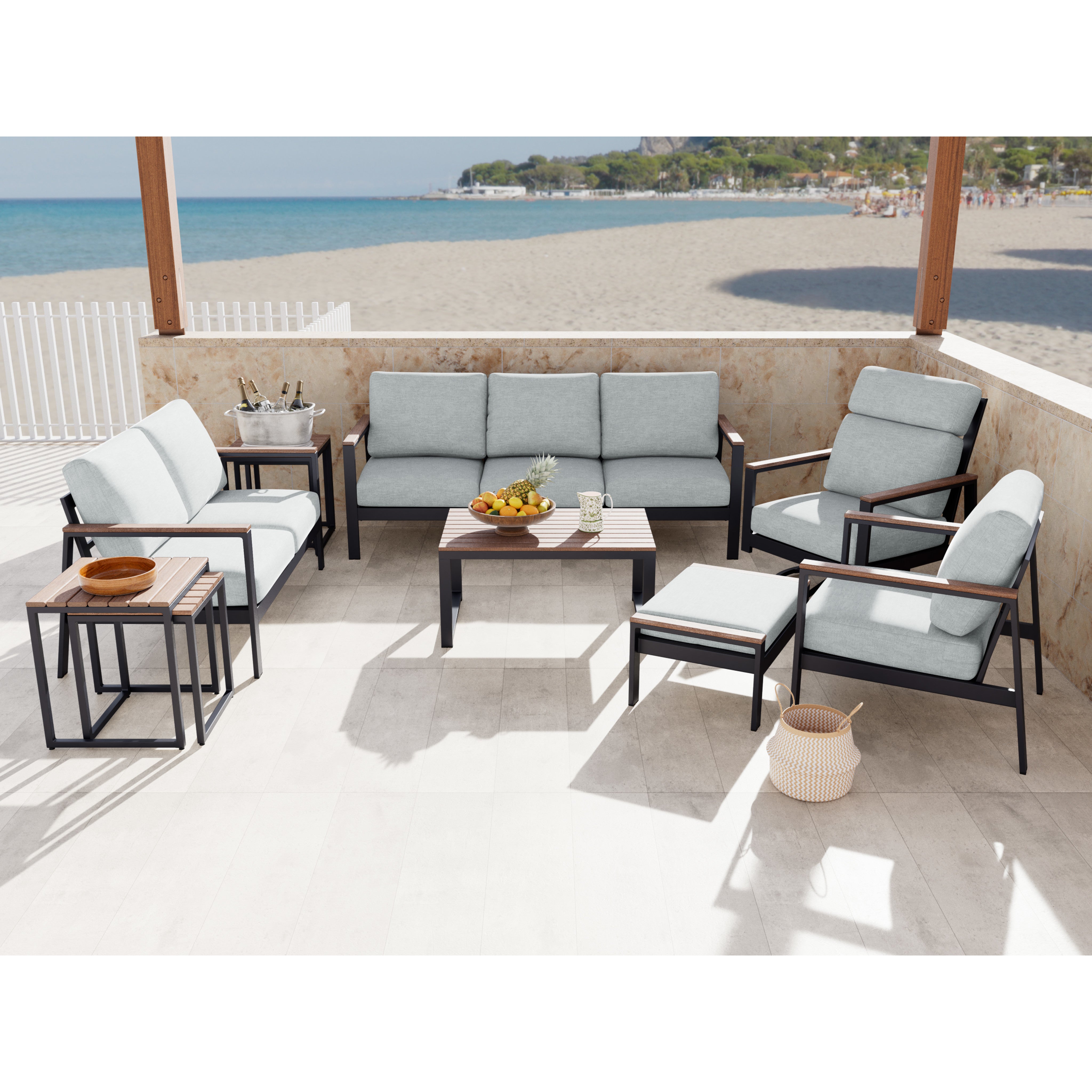 Outdoor patio furniture set with light gray cushions on a beachside terrace.